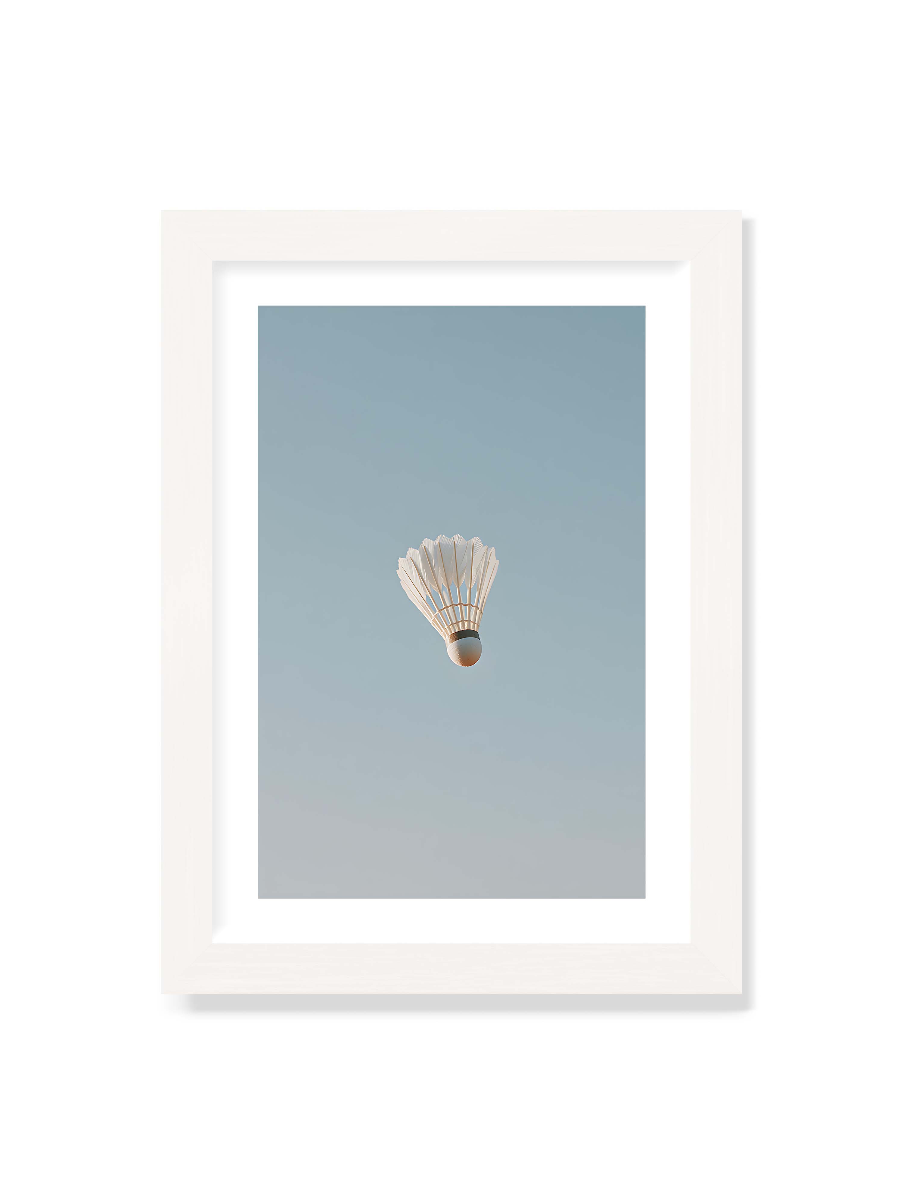 21x30 cm mit weißem Galerie-Rand mit weißem Rahmen – Weißer Federball schwebt zentriert vor hellblauem Himmel, minimalistische Komposition mit viel Freiraum.
