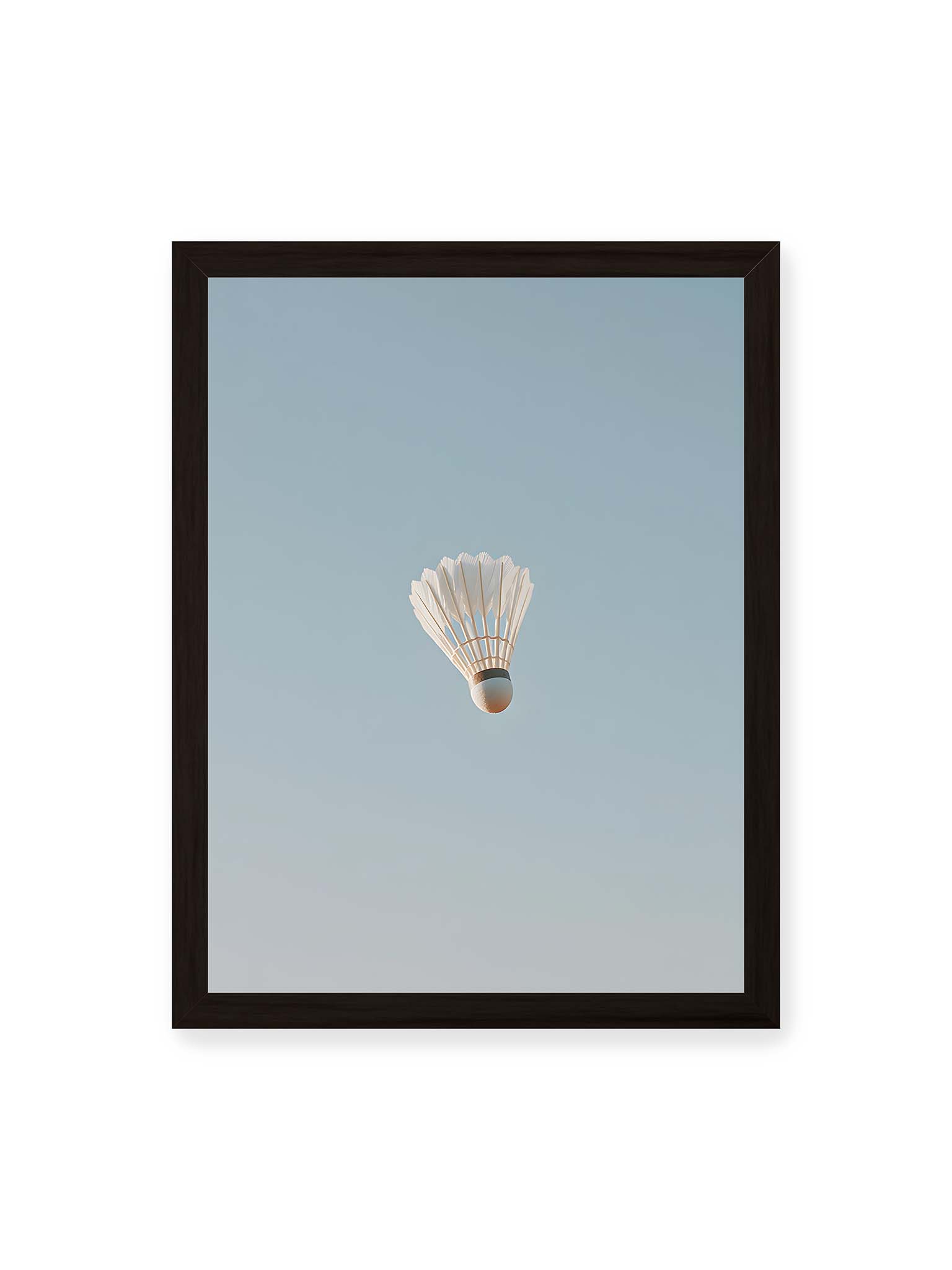30x40 cm, schwarzer Rahmen – Weißer Federball schwebt zentriert vor hellblauem Himmel, minimalistische Komposition mit viel Freiraum.