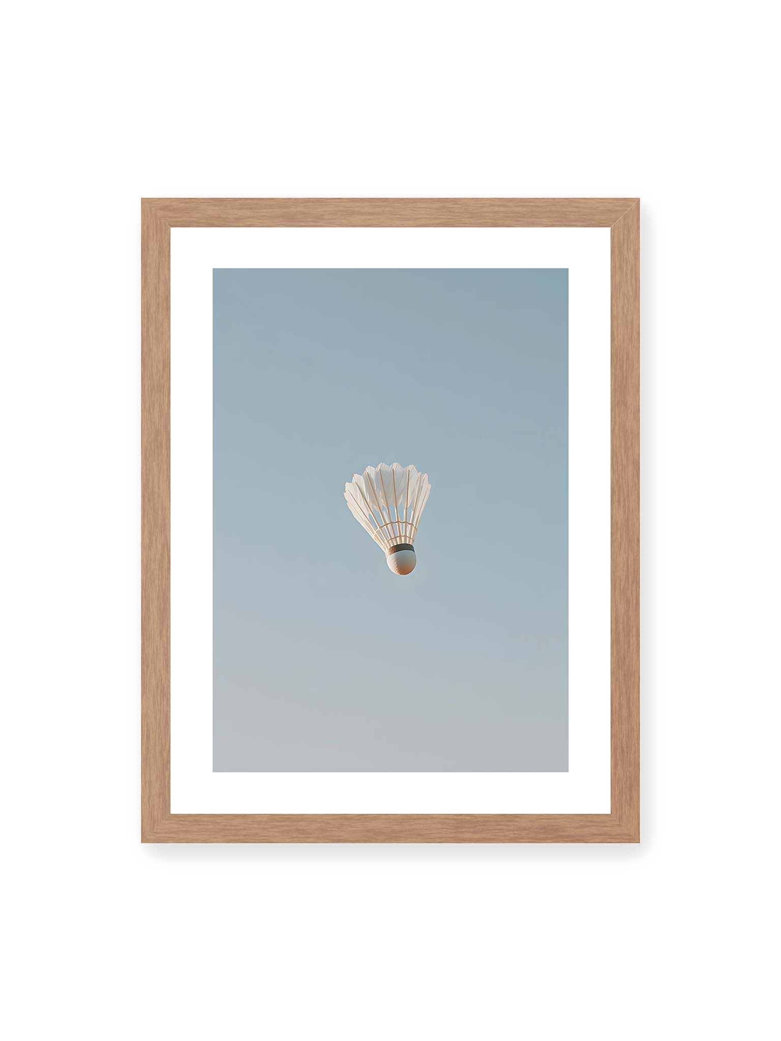 30x40 cm, weißer Galerie-Rand, Eichenrahmen – Weißer Federball schwebt zentriert vor hellblauem Himmel, minimalistische Komposition mit viel Freiraum.