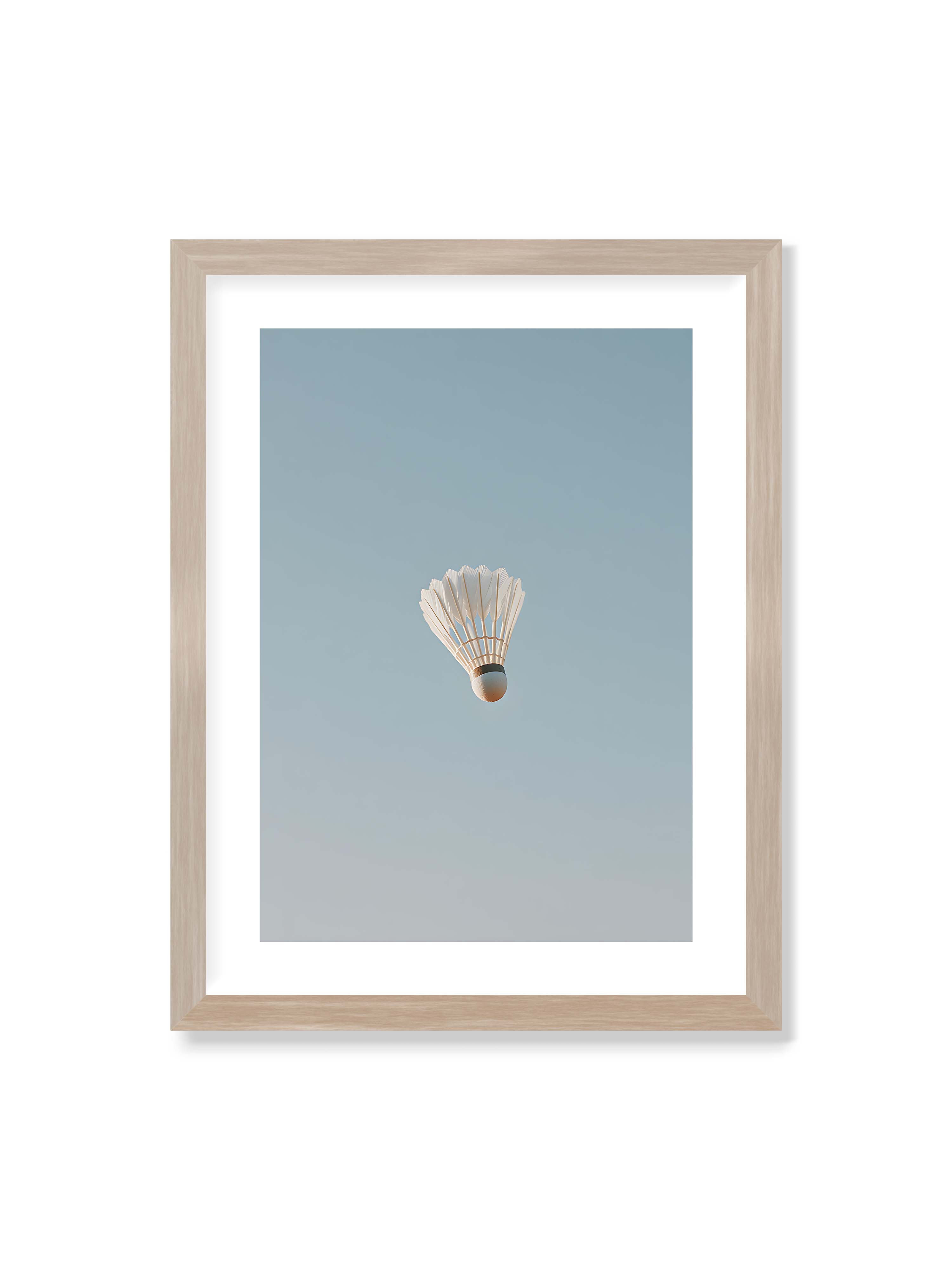 30x40 cm mit weißem Galerie-Rand im Eichenrahmen – Weißer Federball schwebt zentriert vor hellblauem Himmel, minimalistische Komposition mit viel Freiraum.