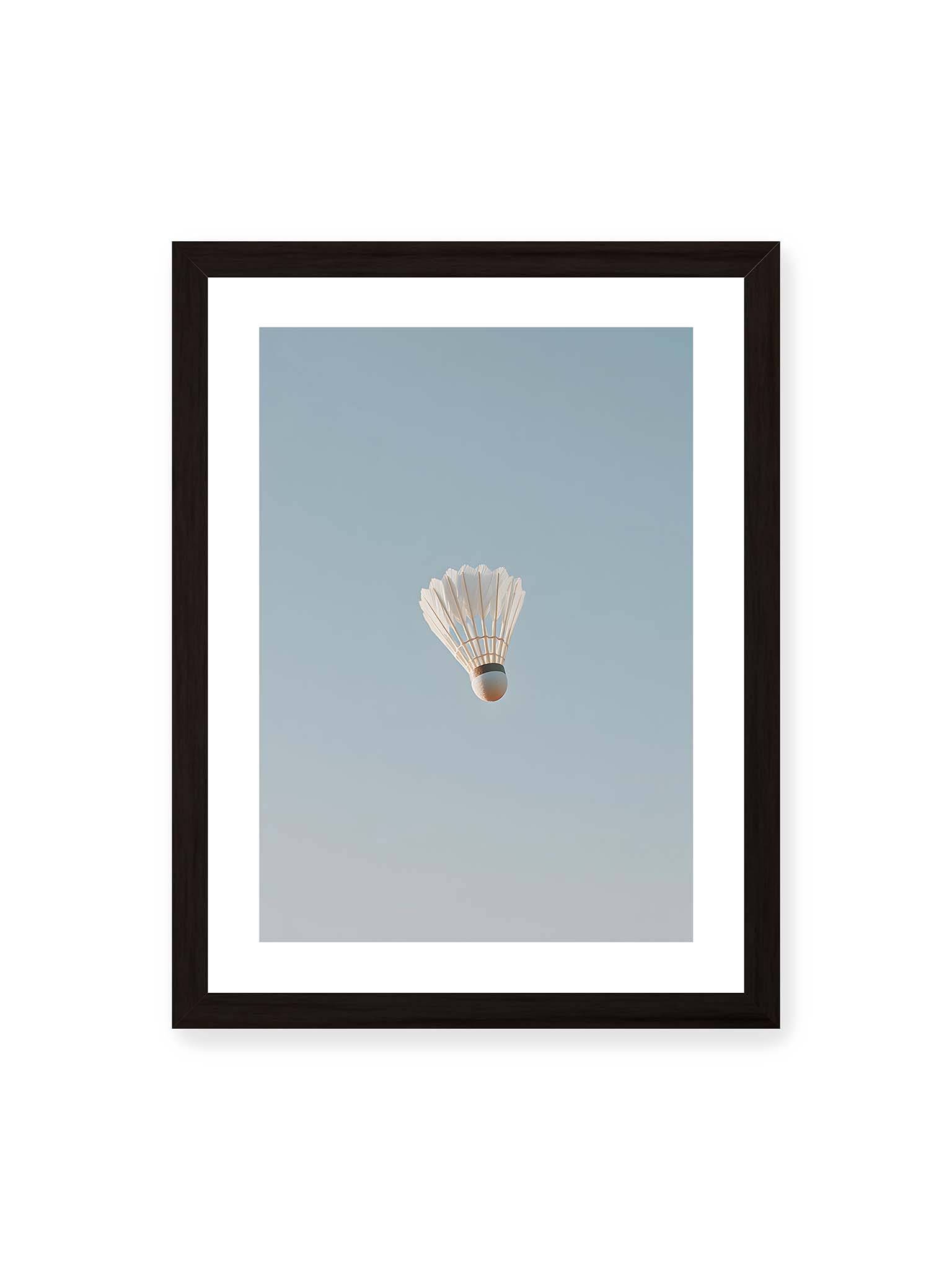 30x40 cm, weißer Galerie-Rand, schwarzer Rahmen – Weißer Federball schwebt zentriert vor hellblauem Himmel, minimalistische Komposition mit viel Freiraum.