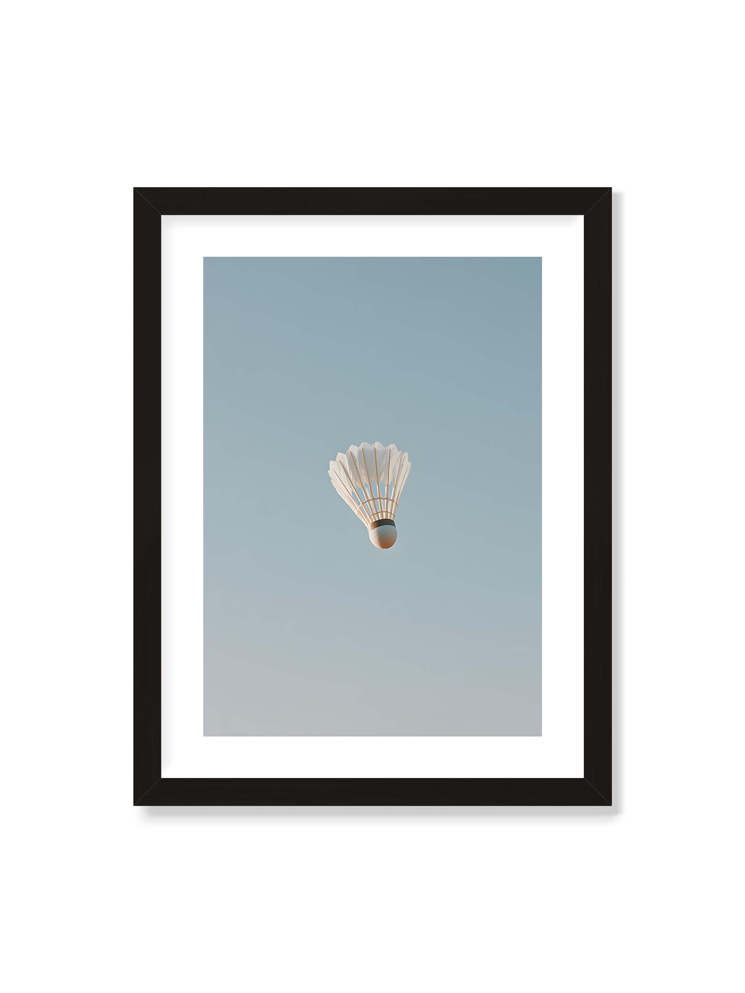 30x40 cm mit weißem Galerie-Rand mit schwarzem Rahmen – Weißer Federball schwebt zentriert vor hellblauem Himmel, minimalistische Komposition mit viel Freiraum.