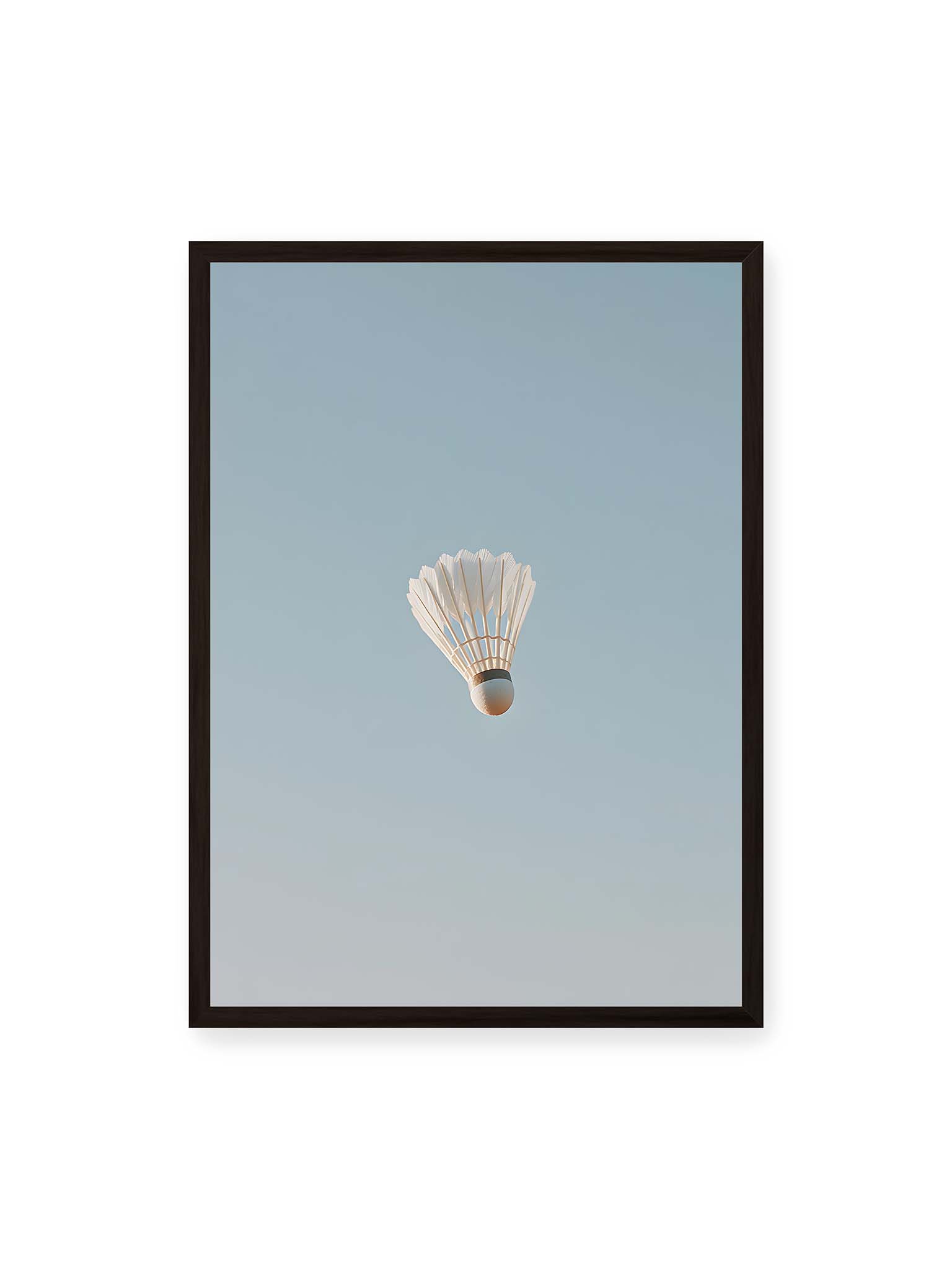 50x70 cm, schwarzer Rahmen – Weißer Federball schwebt zentriert vor hellblauem Himmel, minimalistische Komposition mit viel Freiraum.