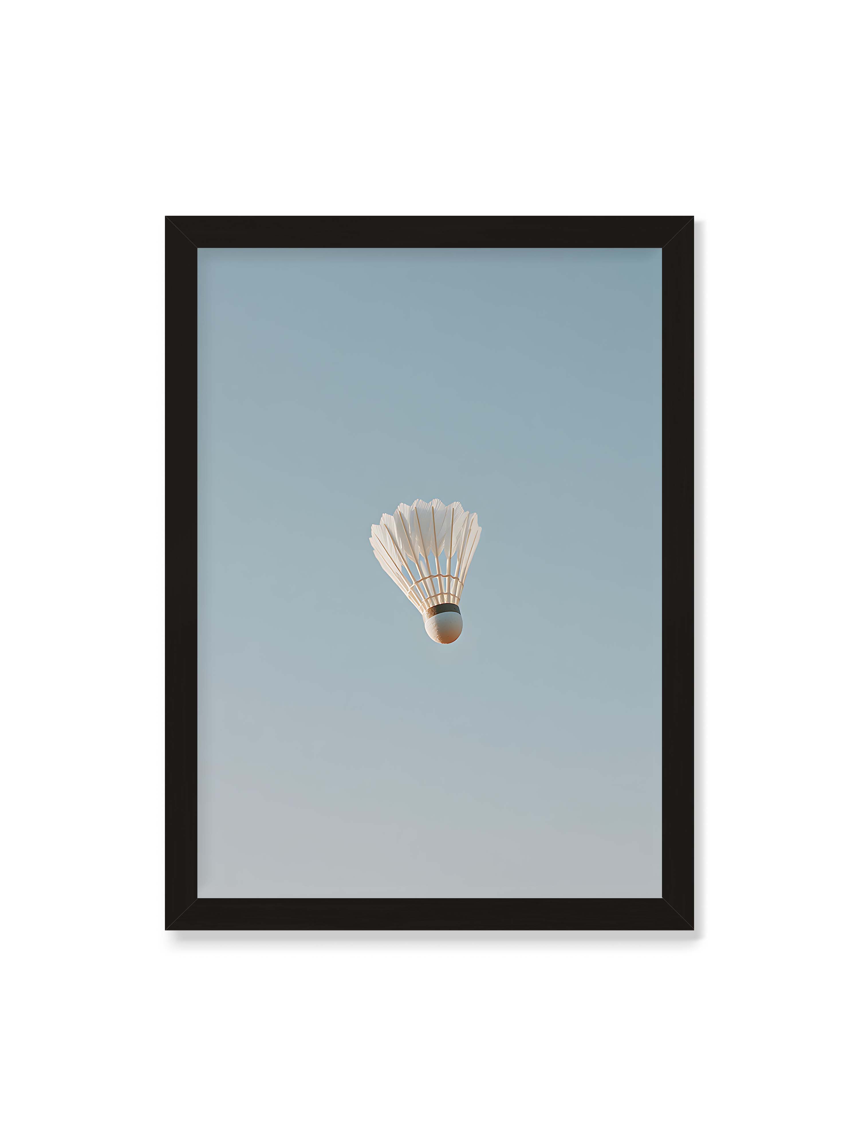50x70 cm ohne Galerie-Rand mit schwarzem Rahmen – Weißer Federball schwebt zentriert vor hellblauem Himmel, minimalistische Komposition mit viel Freiraum.