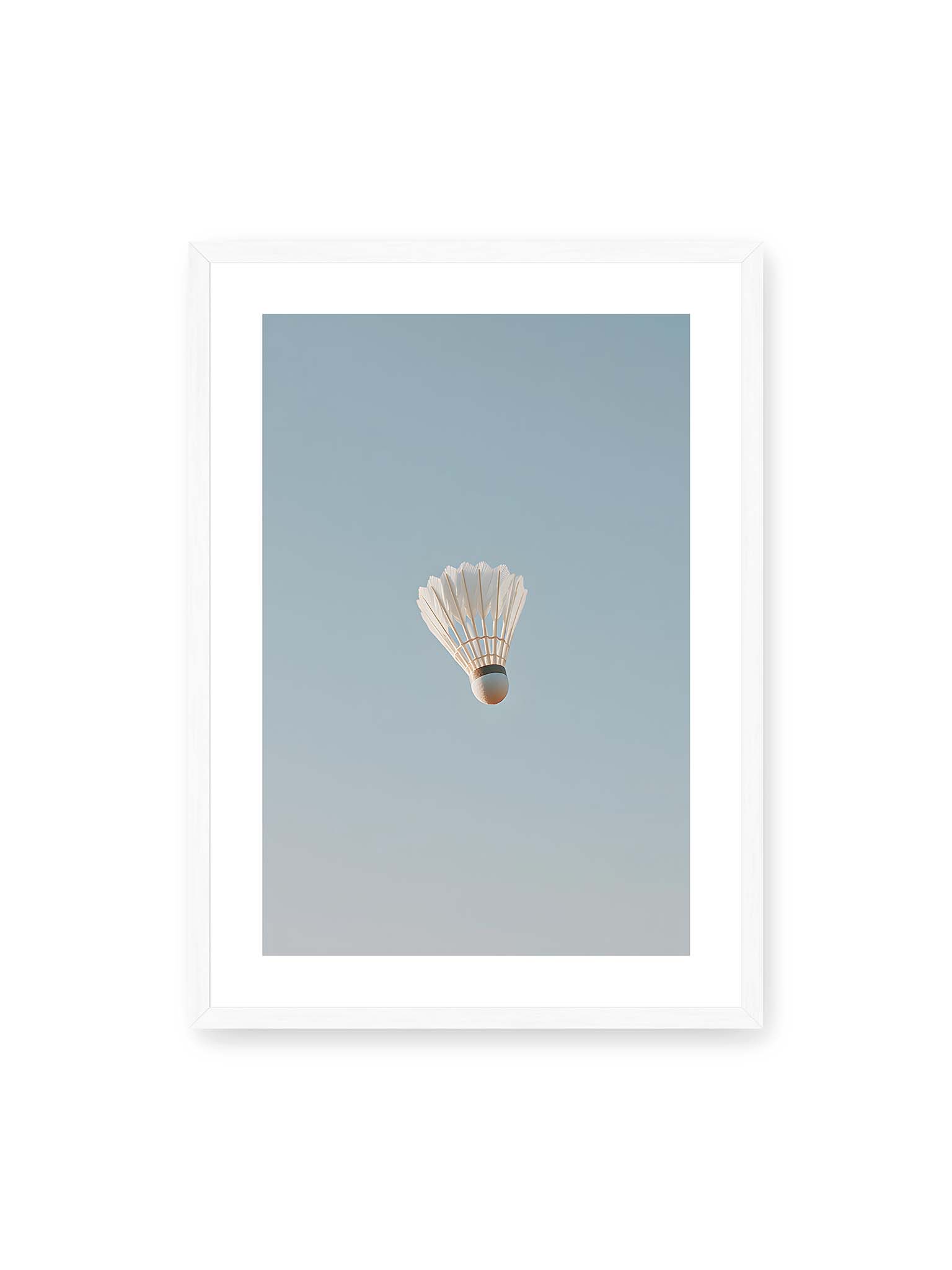 50x70 cm, weißer Galerie-Rand, weißer Rahmen – Weißer Federball schwebt zentriert vor hellblauem Himmel, minimalistische Komposition mit viel Freiraum.