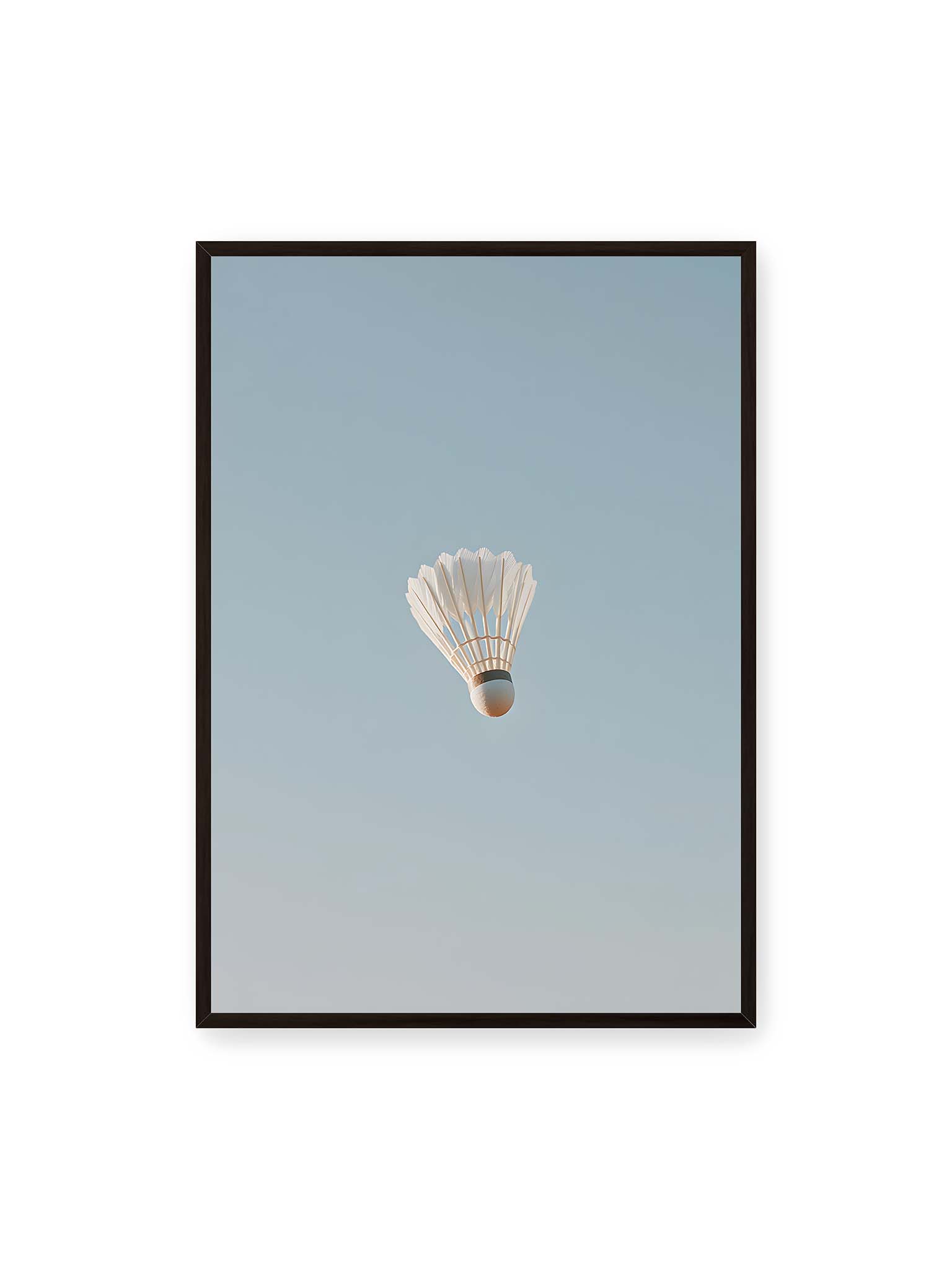 70x100 cm, schwarzer Rahmen – Weißer Federball schwebt zentriert vor hellblauem Himmel, minimalistische Komposition mit viel Freiraum.