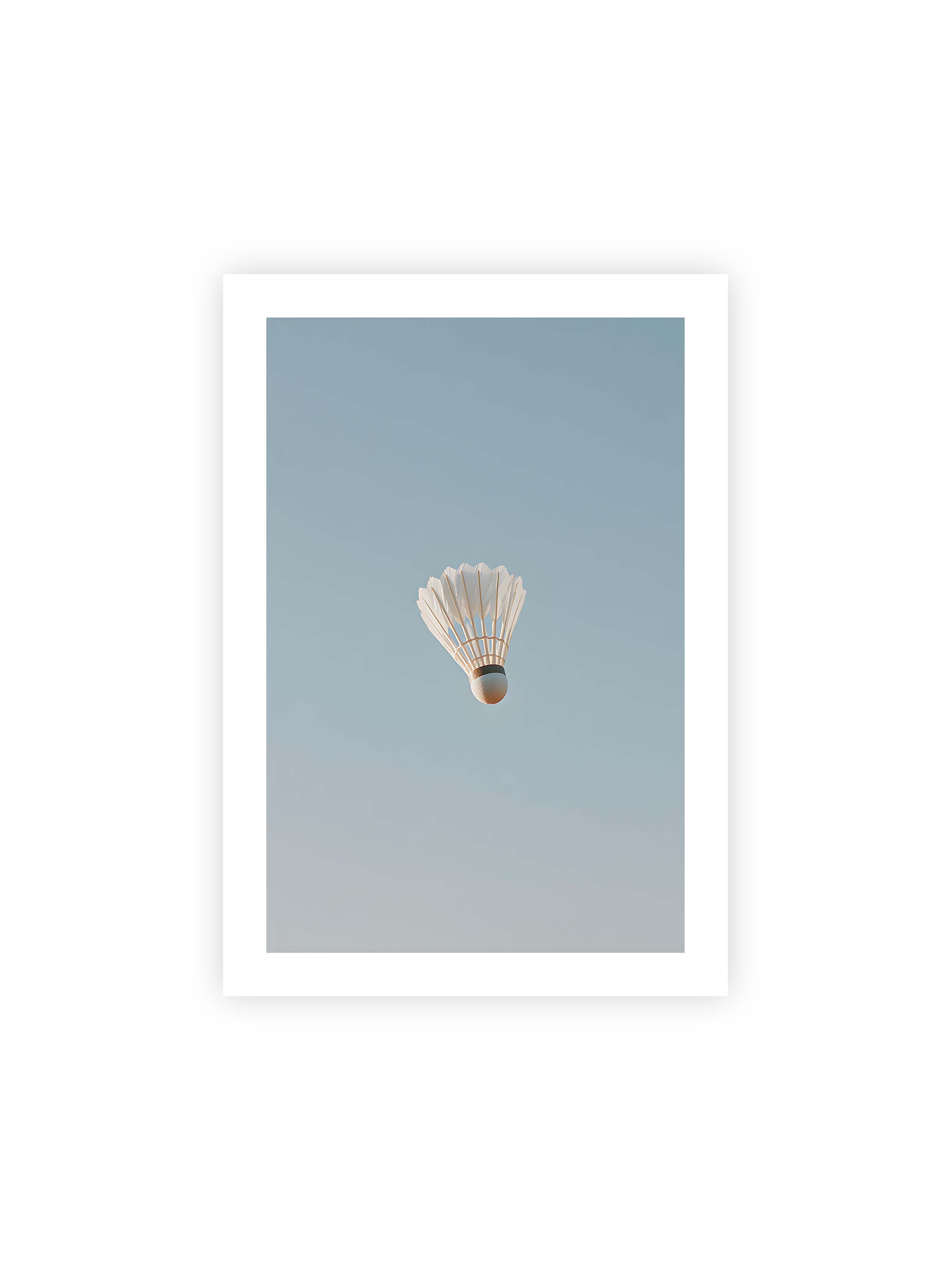 70x100 cm mit weißem Galerie-Rand ohne Rahmen – Weißer Federball schwebt zentriert vor hellblauem Himmel, minimalistische Komposition mit viel Freiraum.