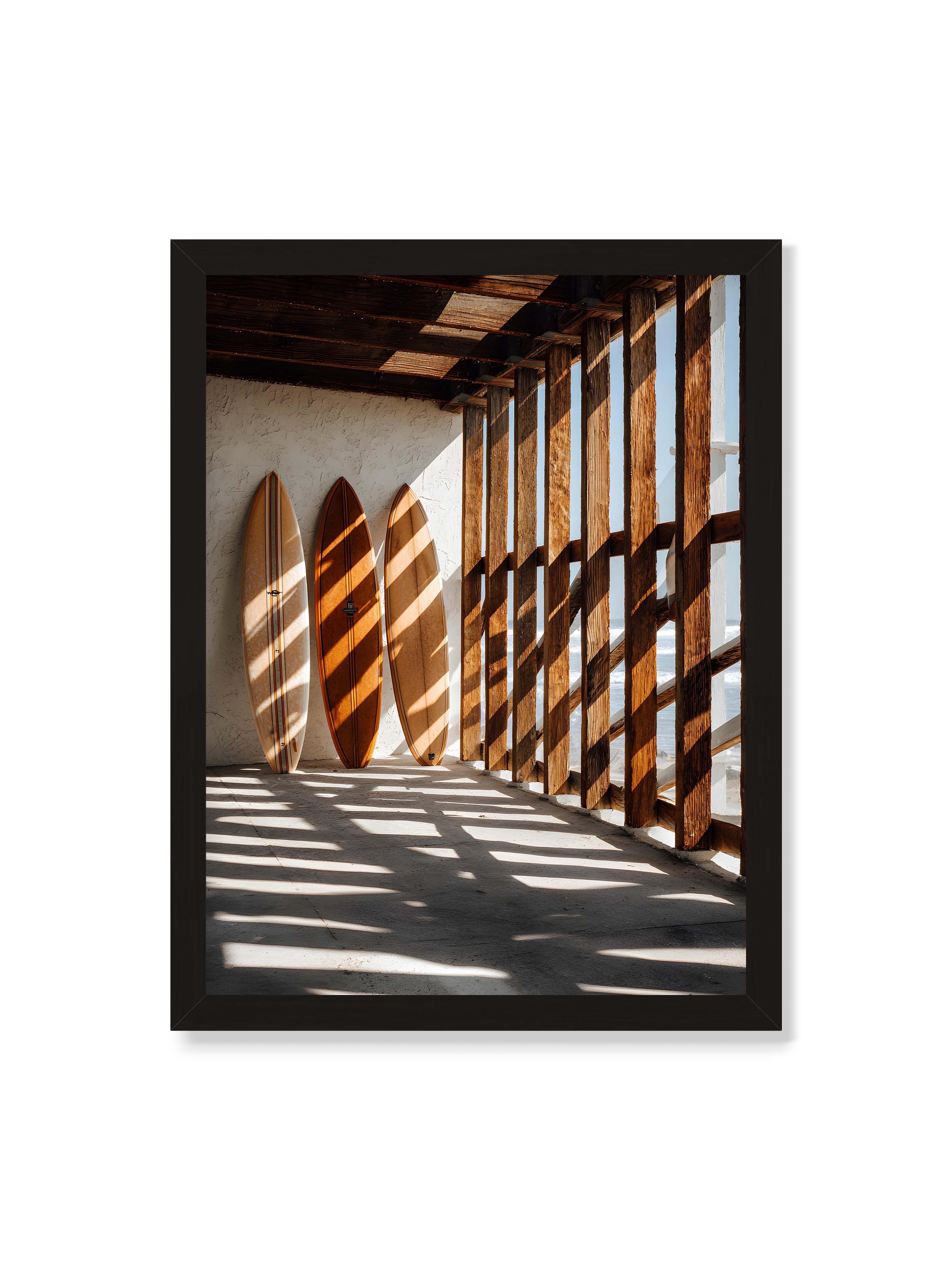 30x40 cm ohne Galerie-Rand mit schwarzem Rahmen – Drei Surfboards an einer hellen Wand, Holzpfosten werfen diagonale Schatten; Meer und Himmel schimmern im Hintergrund.