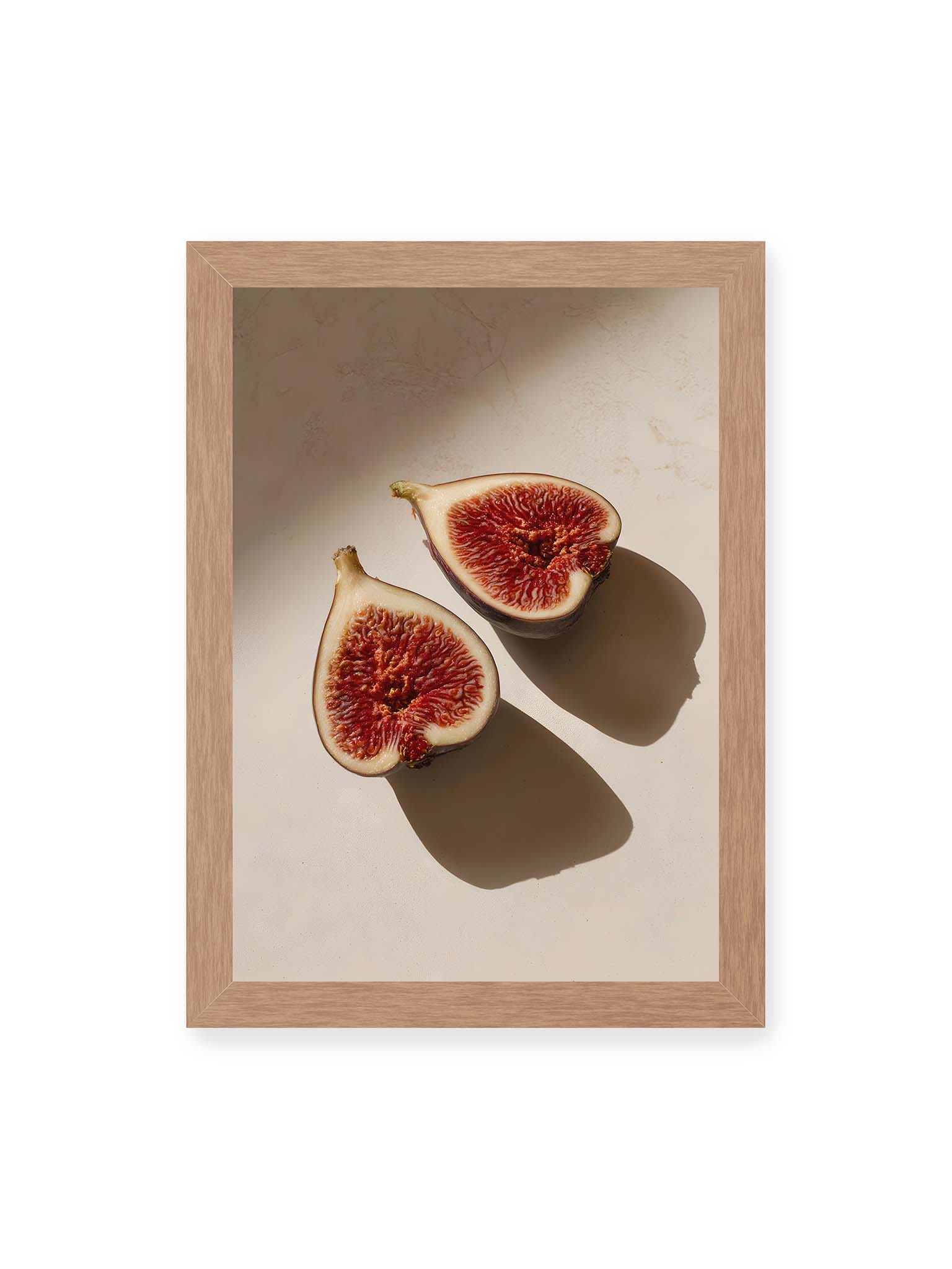 21x30 cm, Eichenrahmen – Halbierte Feigen auf heller Oberfläche mit warmem Licht und langen Schatten, sichtbar strukturierte rote Fruchtmitte.