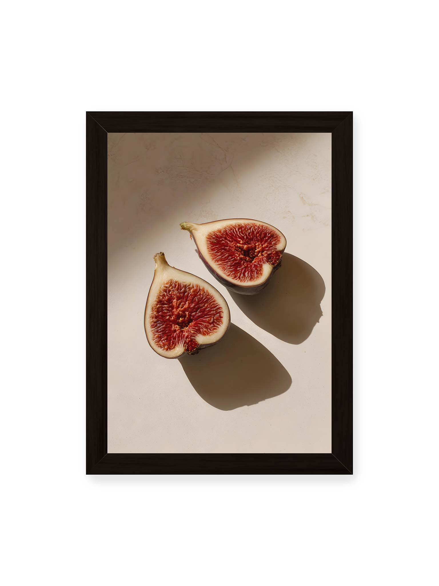 21x30 cm, schwarzer Rahmen – Halbierte Feigen auf heller Oberfläche mit warmem Licht und langen Schatten, sichtbar strukturierte rote Fruchtmitte.