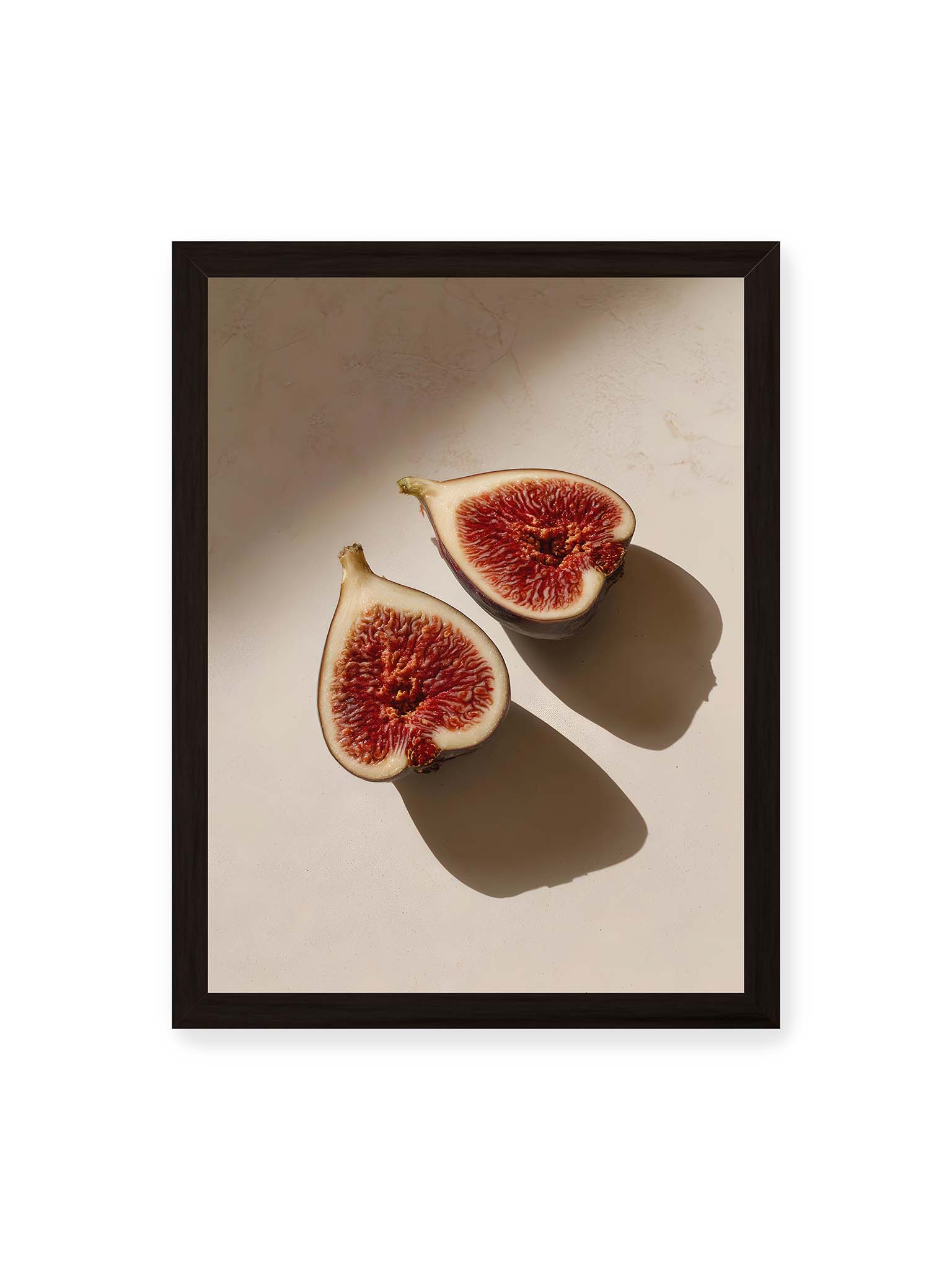 30x40 cm, schwarzer Rahmen – Halbierte Feigen auf heller Oberfläche mit warmem Licht und langen Schatten, sichtbar strukturierte rote Fruchtmitte.