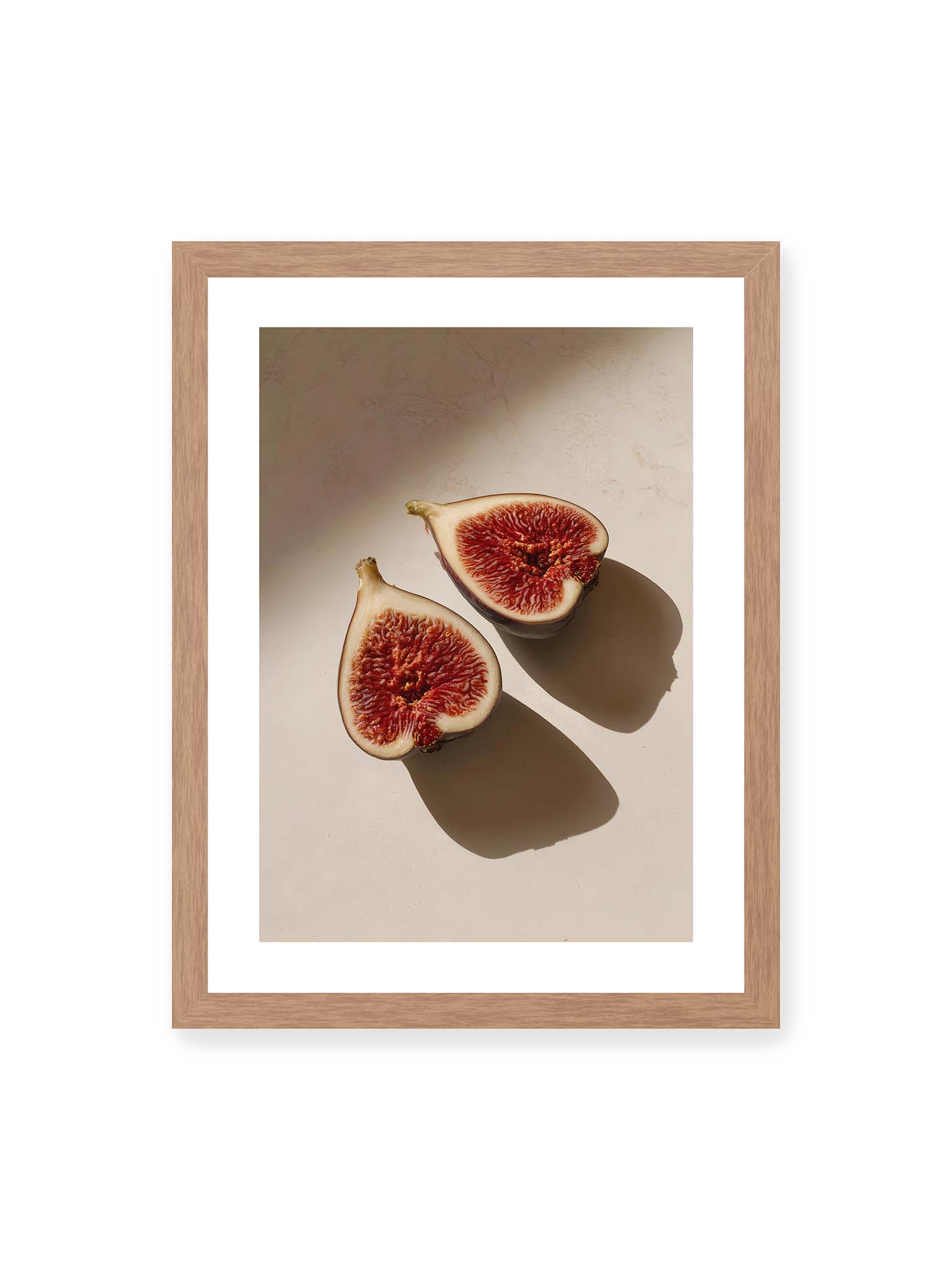 30x40 cm, weißer Galerie-Rand, Eichenrahmen – Halbierte Feigen auf heller Oberfläche mit warmem Licht und langen Schatten, sichtbar strukturierte rote Fruchtmitte.