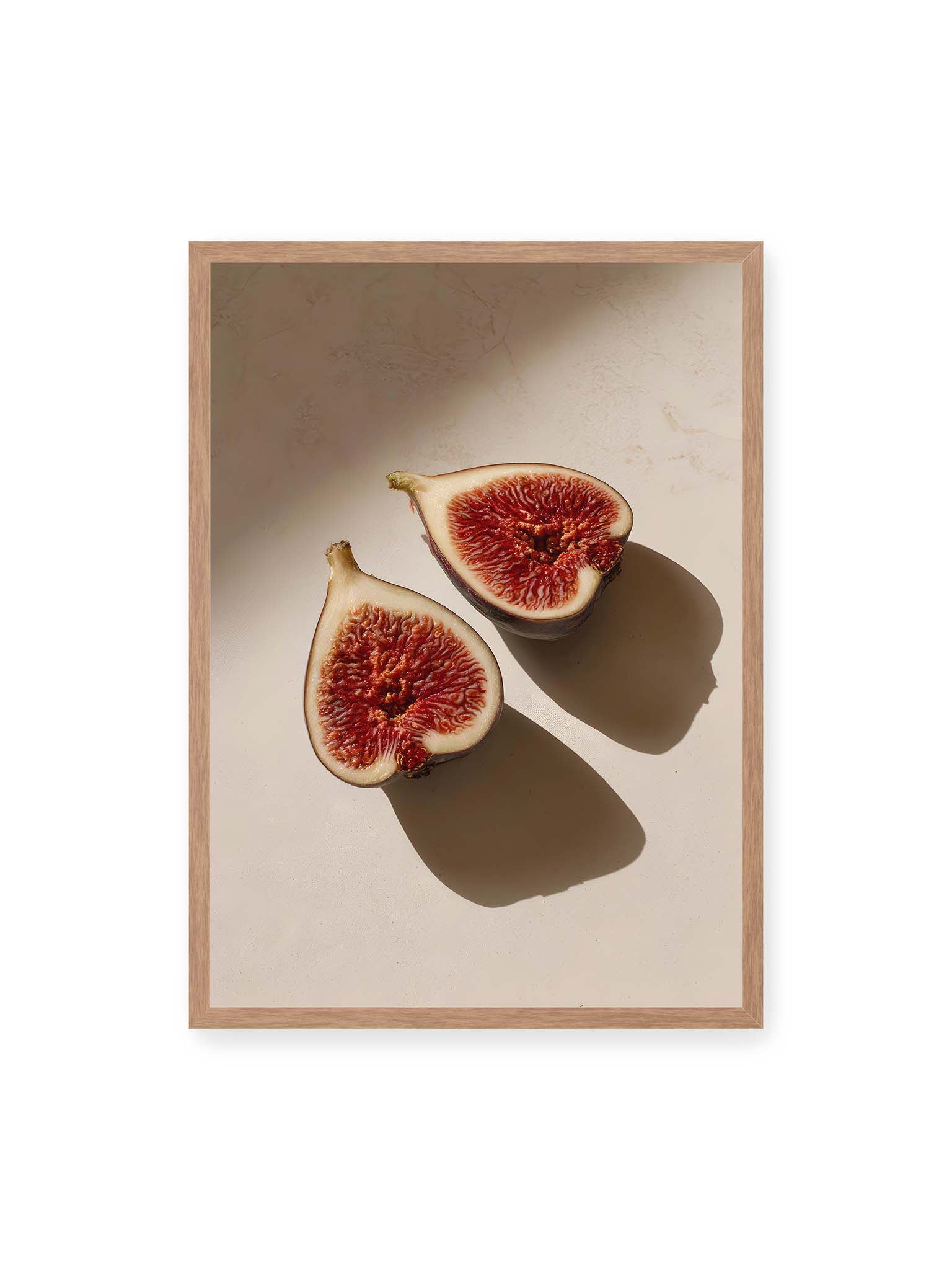 50x70 cm, Eichenrahmen – Halbierte Feigen auf heller Oberfläche mit warmem Licht und langen Schatten, sichtbar strukturierte rote Fruchtmitte.