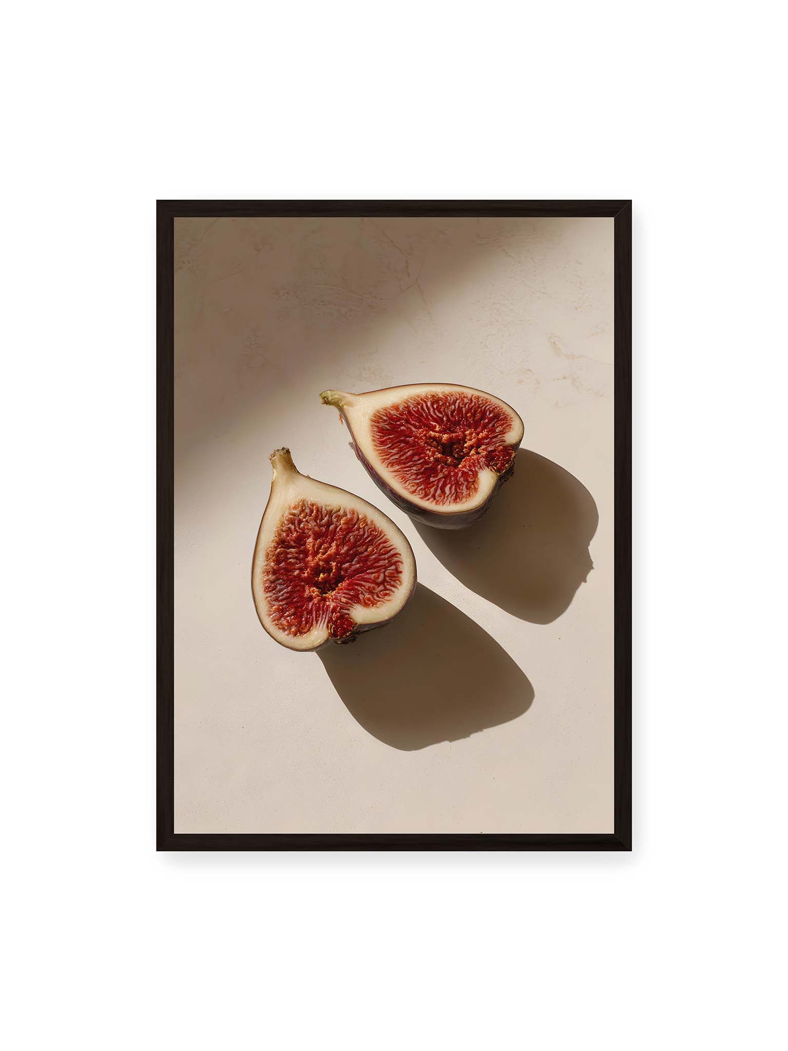 50x70 cm, schwarzer Rahmen – Halbierte Feigen auf heller Oberfläche mit warmem Licht und langen Schatten, sichtbar strukturierte rote Fruchtmitte.