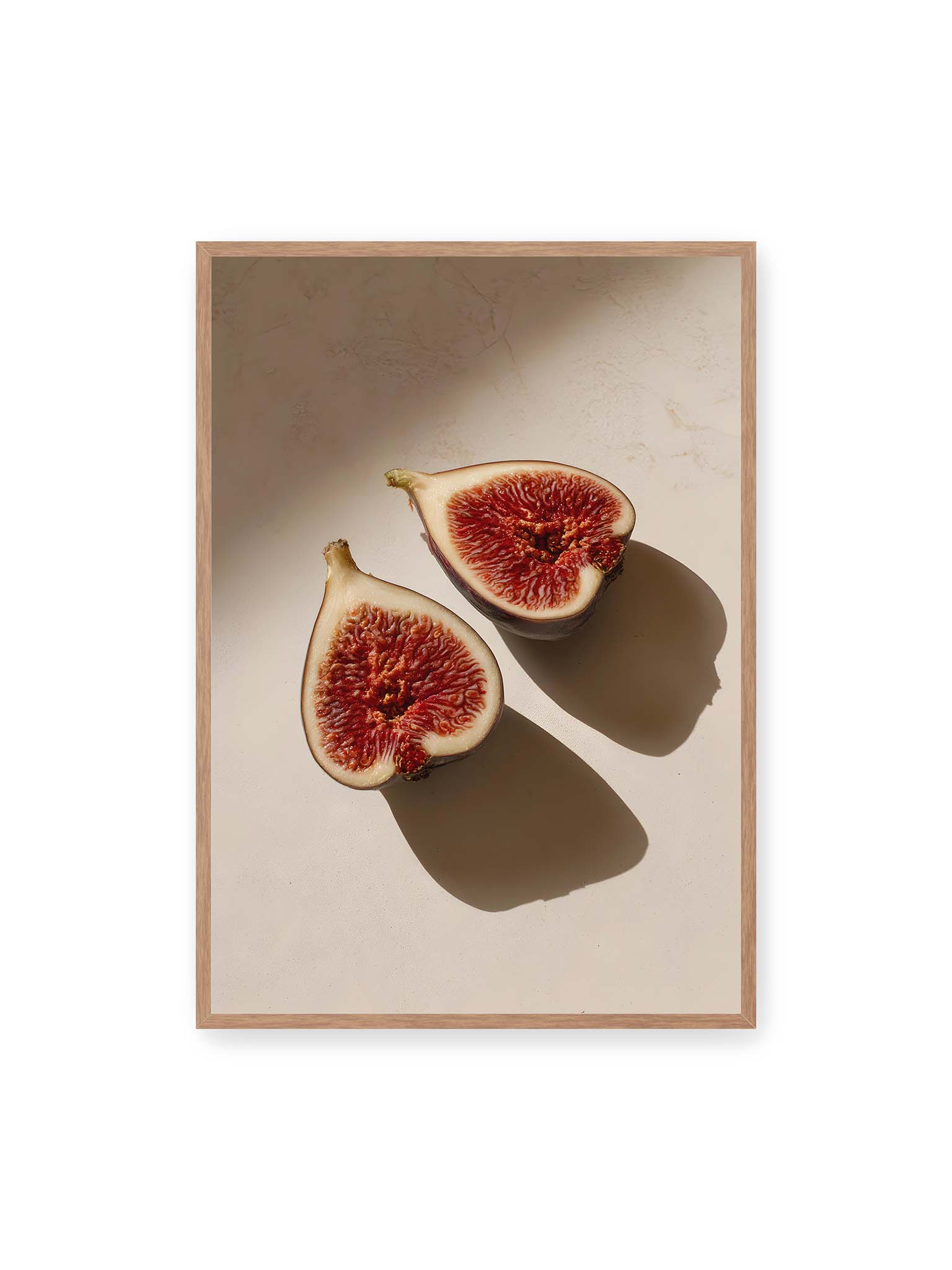 70x100 cm, Eichenrahmen – Halbierte Feigen auf heller Oberfläche mit warmem Licht und langen Schatten, sichtbar strukturierte rote Fruchtmitte.