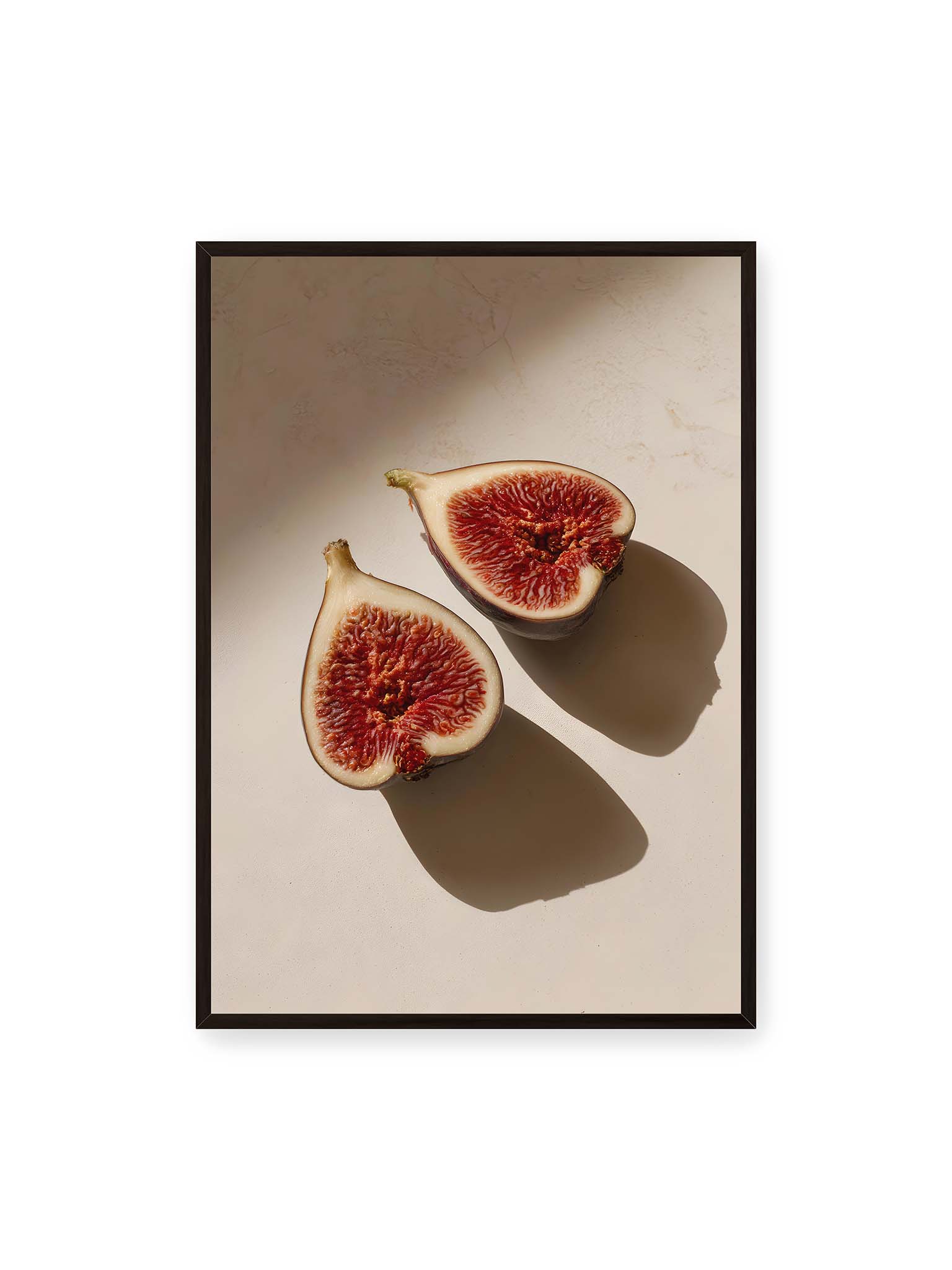 70x100 cm, schwarzer Rahmen – Halbierte Feigen auf heller Oberfläche mit warmem Licht und langen Schatten, sichtbar strukturierte rote Fruchtmitte.