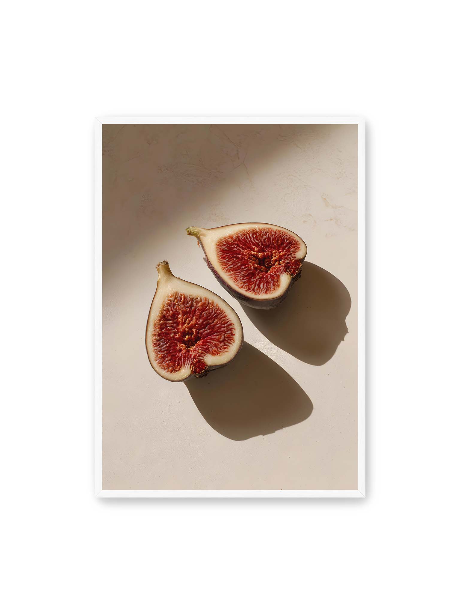 70x100 cm, weißer Rahmen – Halbierte Feigen auf heller Oberfläche mit warmem Licht und langen Schatten, sichtbar strukturierte rote Fruchtmitte.