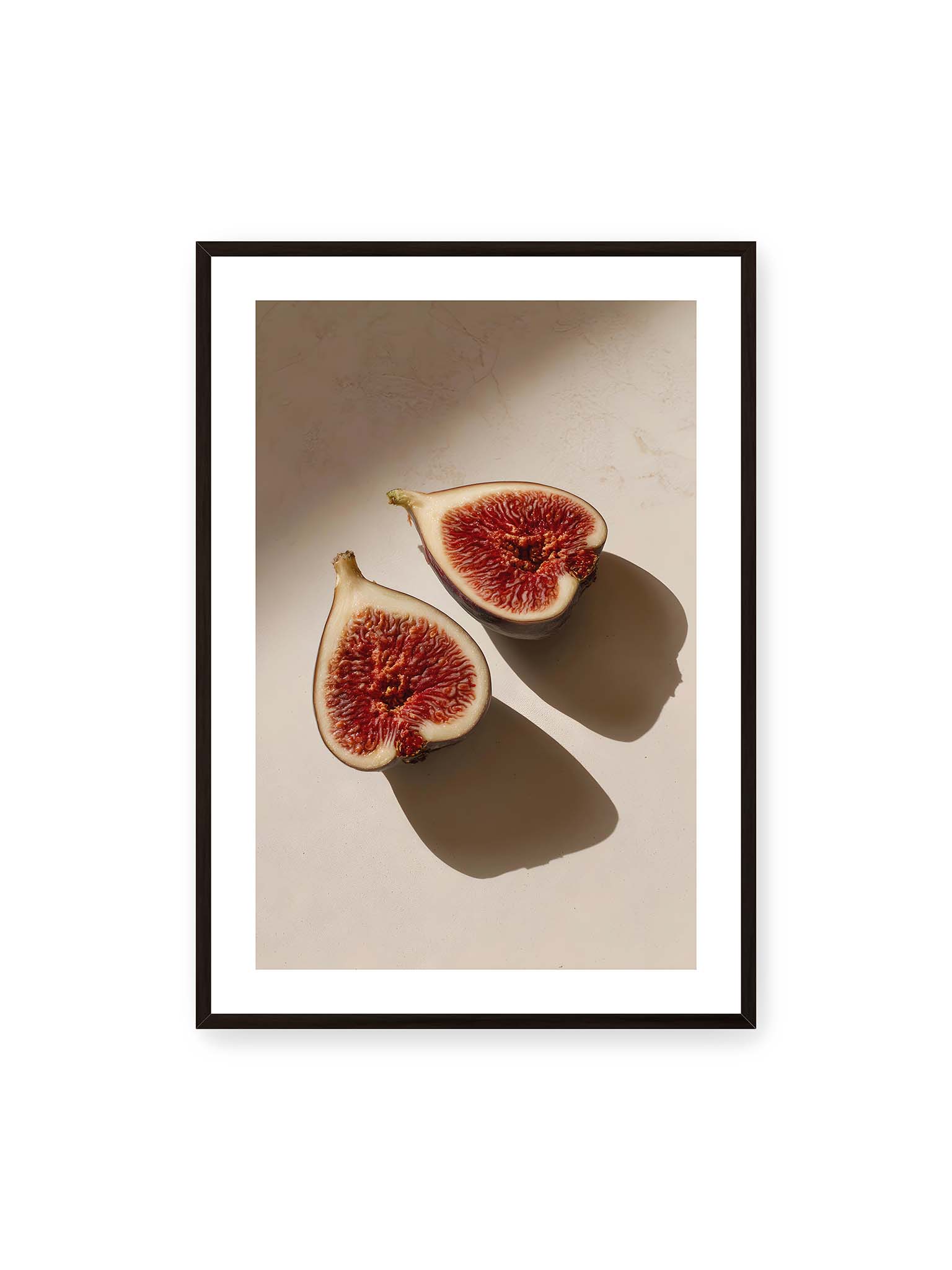 70x100 cm, weißer Galerie-Rand, schwarzer Rahmen – Halbierte Feigen auf heller Oberfläche mit warmem Licht und langen Schatten, sichtbar strukturierte rote Fruchtmitte.