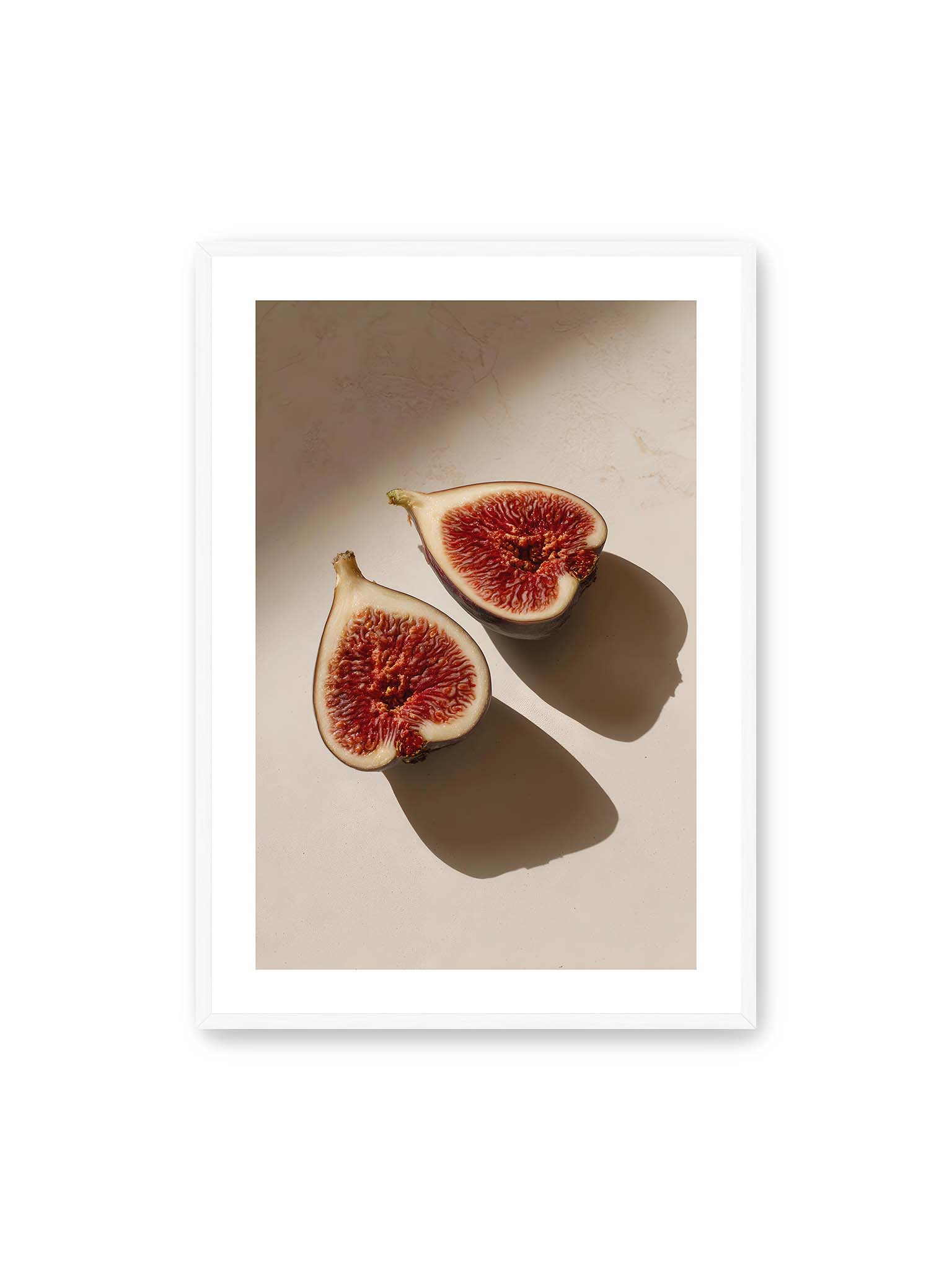 70x100 cm, weißer Galerie-Rand, weißer Rahmen – Halbierte Feigen auf heller Oberfläche mit warmem Licht und langen Schatten, sichtbar strukturierte rote Fruchtmitte.