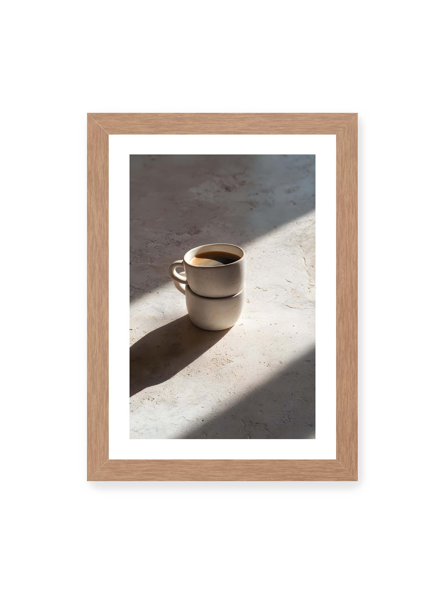 21x30 cm, weißer Galerie-Rand, Eichenrahmen – Zwei gestapelte Keramiktassen mit schwarzem Kaffee auf heller Oberfläche, beleuchtet von schrägem Morgenlicht mit langen Schatten.
