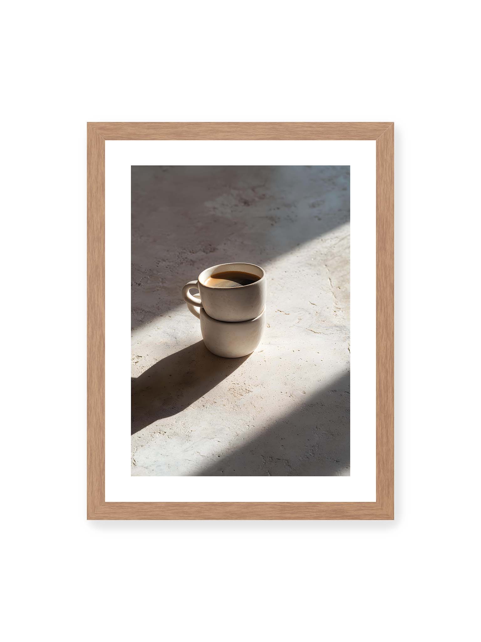 30x40 cm, weißer Galerie-Rand, Eichenrahmen – Zwei gestapelte Keramiktassen mit schwarzem Kaffee auf heller Oberfläche, beleuchtet von schrägem Morgenlicht mit langen Schatten.