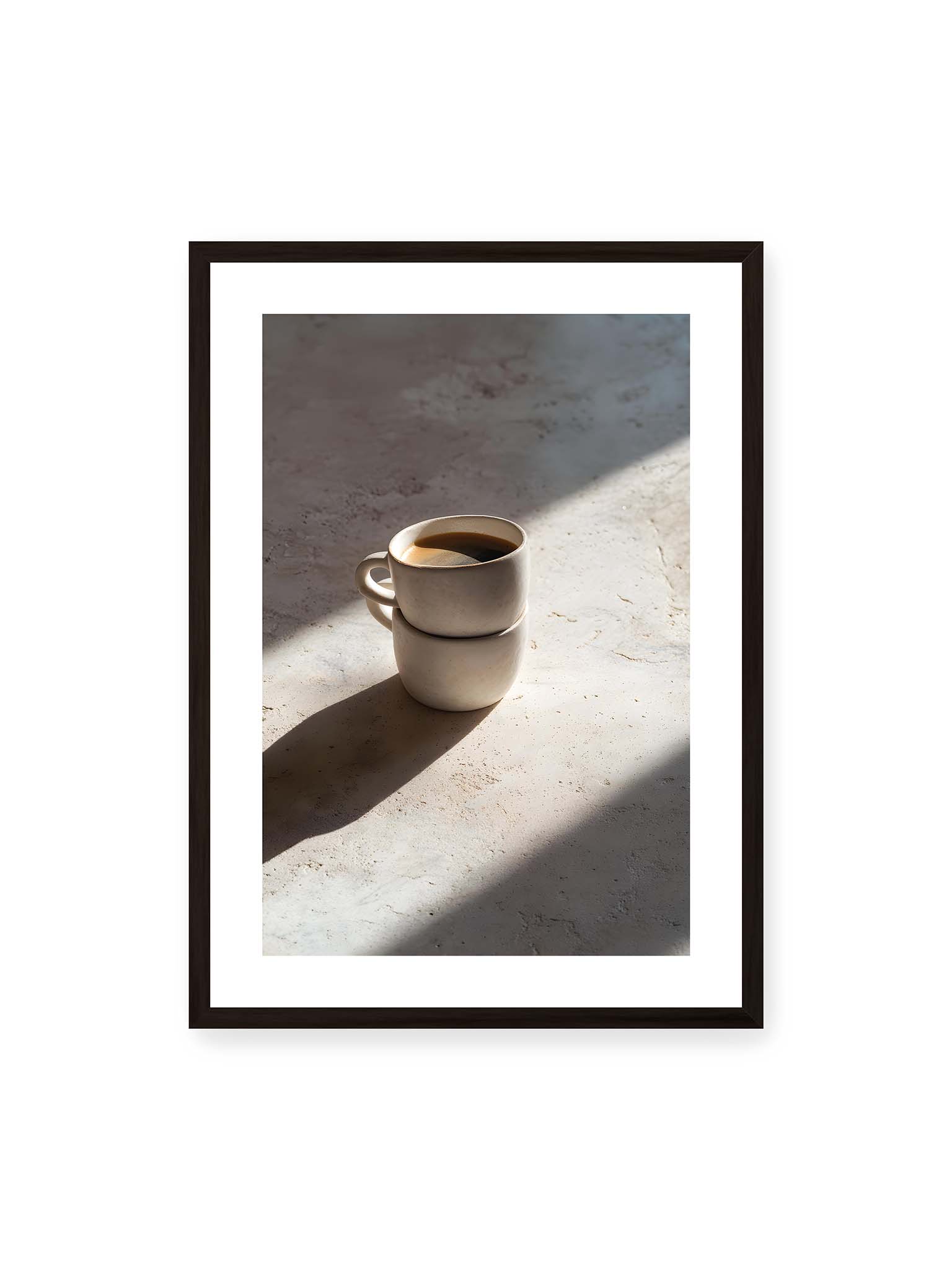 50x70 cm, weißer Galerie-Rand, schwarzer Rahmen – Zwei gestapelte Keramiktassen mit schwarzem Kaffee auf heller Oberfläche, beleuchtet von schrägem Morgenlicht mit langen Schatten.