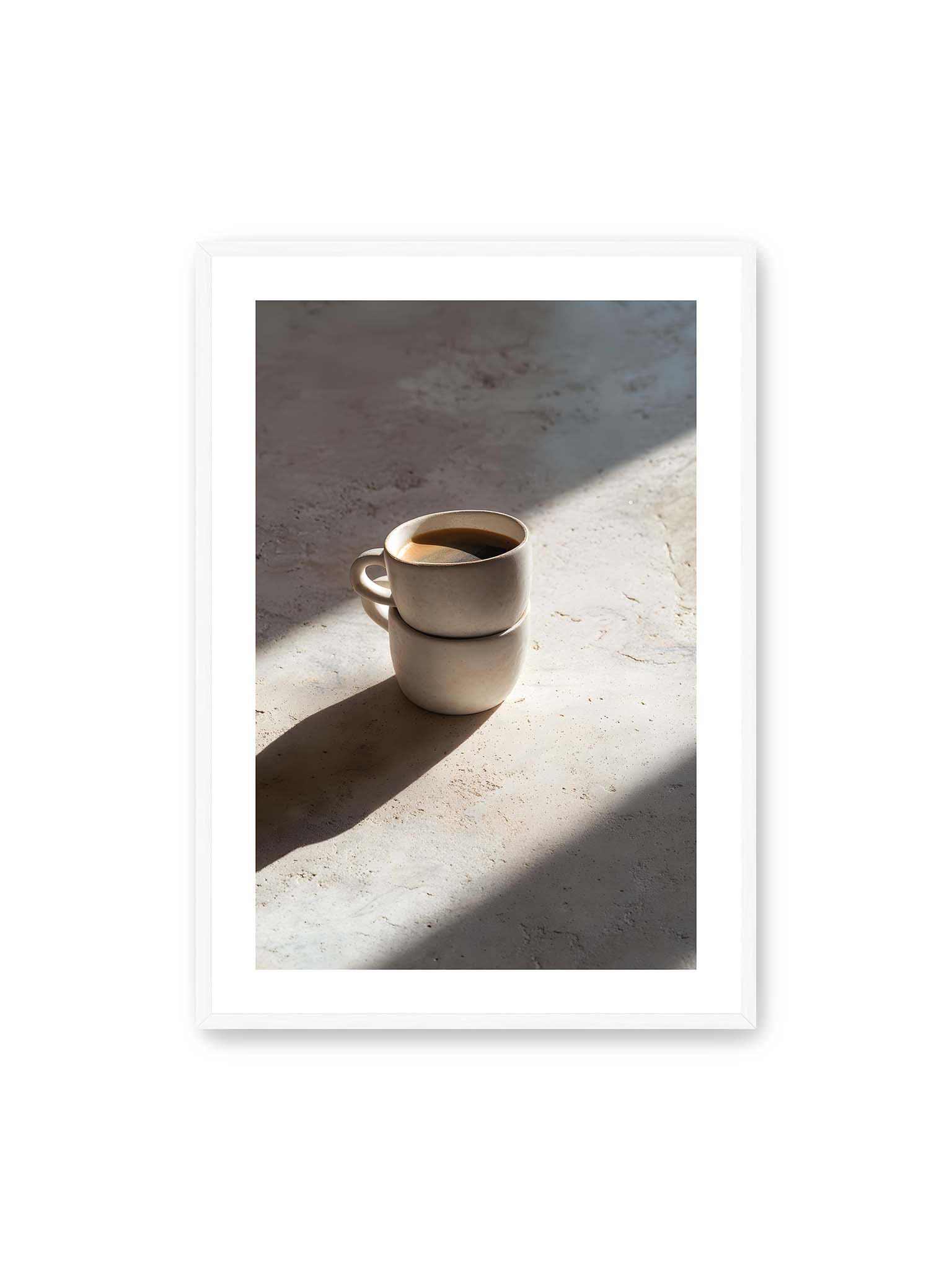 70x100 cm, weißer Galerie-Rand, weißer Rahmen – Zwei gestapelte Keramiktassen mit schwarzem Kaffee auf heller Oberfläche, beleuchtet von schrägem Morgenlicht mit langen Schatten.