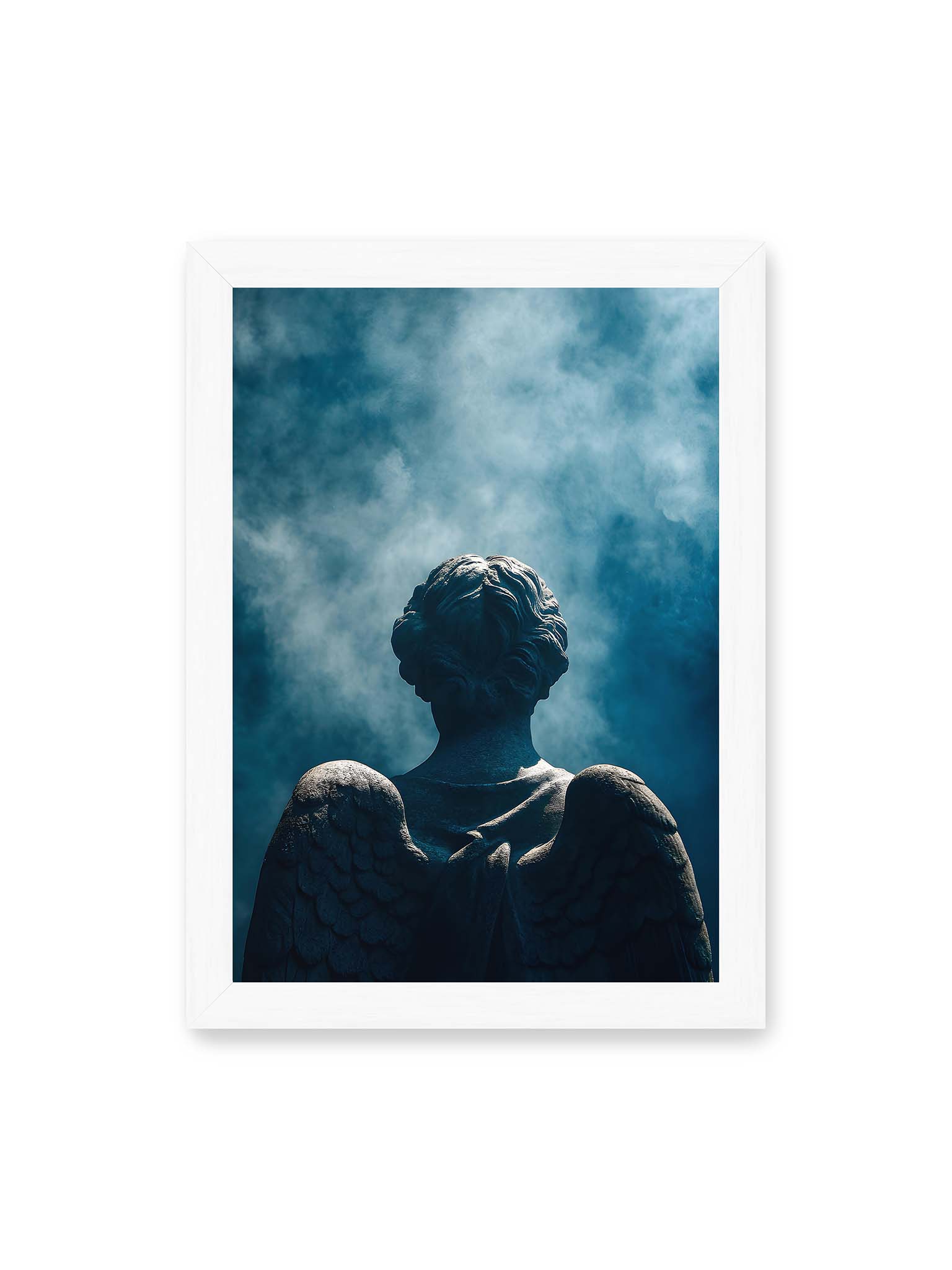 21x30 cm, weißer Rahmen – Rückansicht einer steinernen Engelsfigur mit ausgebreiteten Flügeln vor blauem Himmel und aufsteigendem Nebel.