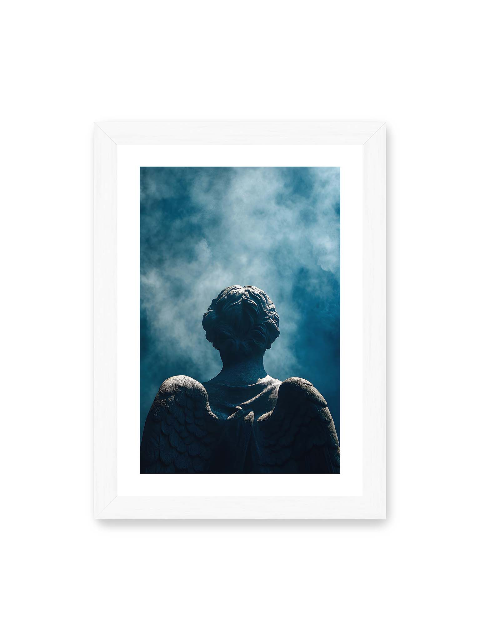 21x30 cm, weißer Galerie-Rand, weißer Rahmen – Rückansicht einer steinernen Engelsfigur mit ausgebreiteten Flügeln vor blauem Himmel und aufsteigendem Nebel.