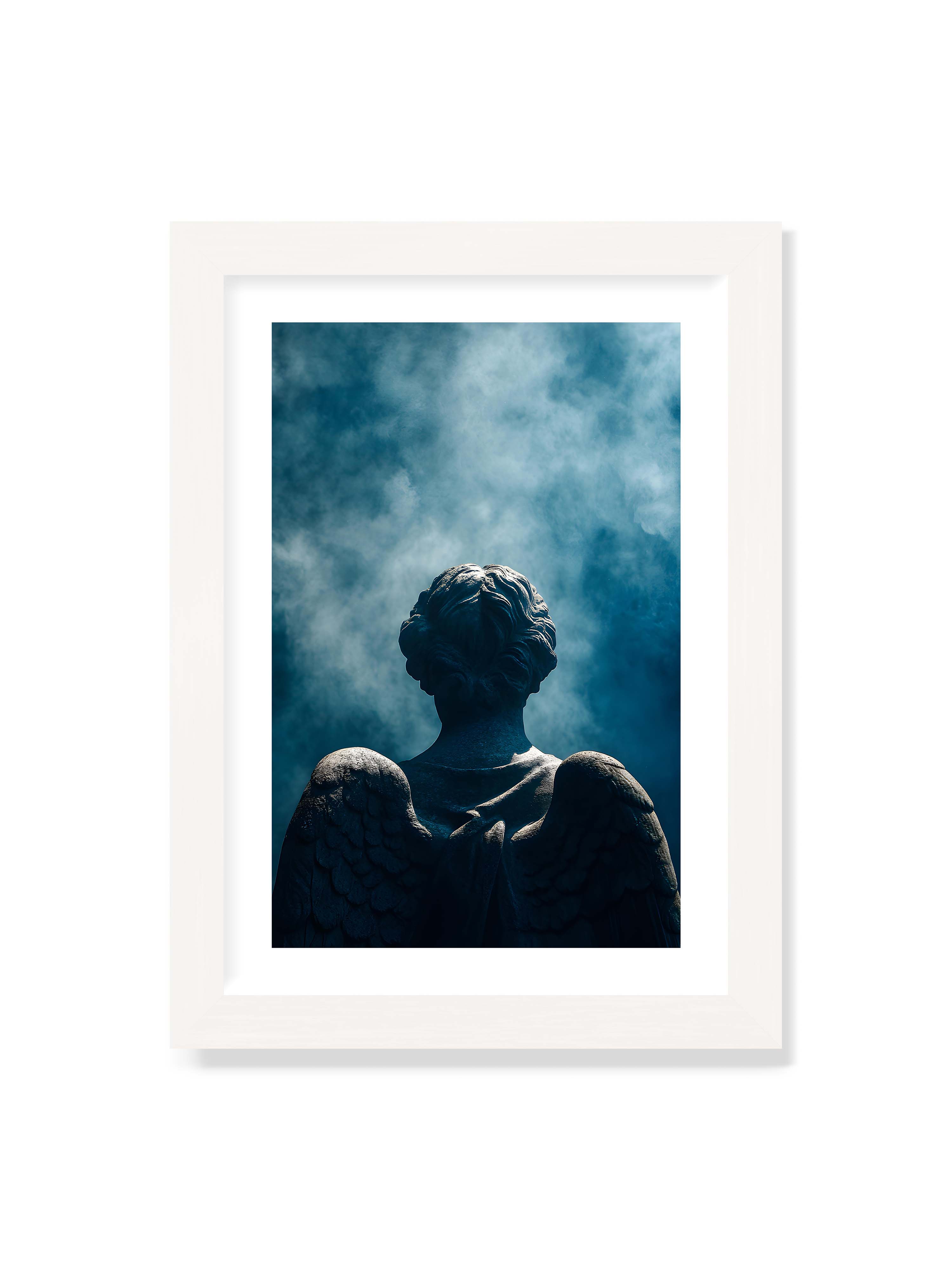 21x30 cm mit weißem Galerie-Rand mit weißem Rahmen – Steinerne Engelsfigur von hinten mit ausgebreiteten Flügeln vor blauem, nebligem Himmel.