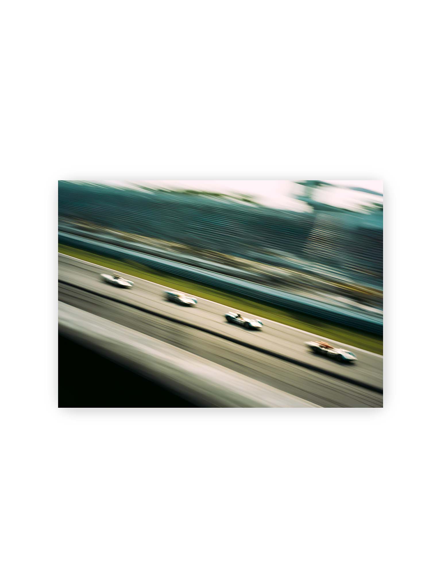 21x30 cm – Mehrere Rennwagen in starker Bewegungsunschärfe auf einer Rennstrecke, diagonal ausgerichtet.