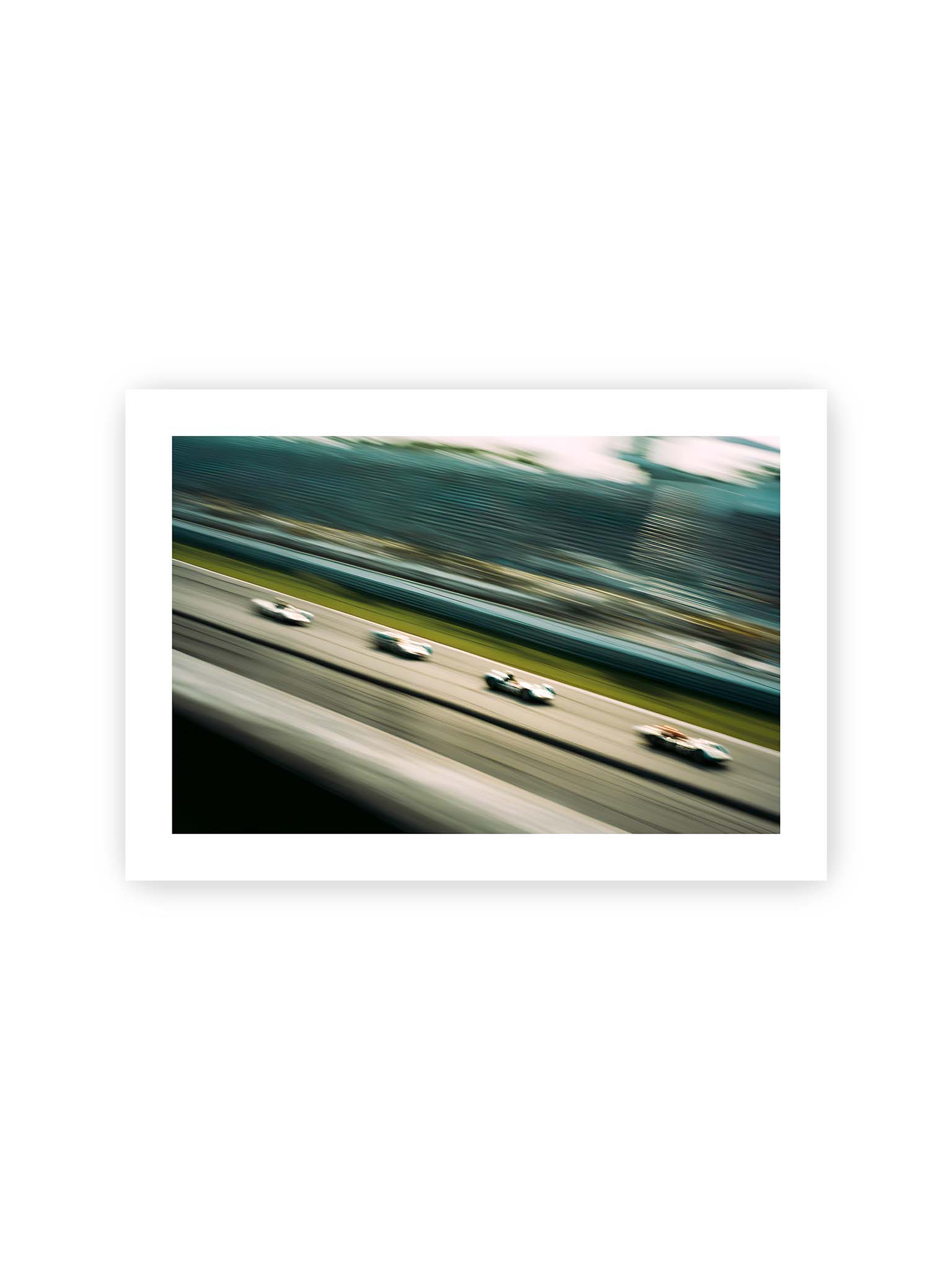 21x30 cm, weißer Galerie-Rand – Mehrere Rennwagen in starker Bewegungsunschärfe auf einer Rennstrecke, diagonal ausgerichtet.
