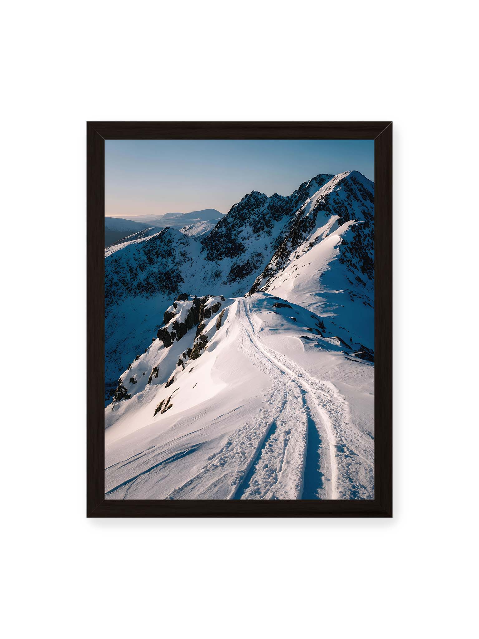 30x40 cm, schwarzer Rahmen – Verschneiter Bergpfad, sanftes Licht beleuchtet die Spuren im Schnee, Berge im Hintergrund.