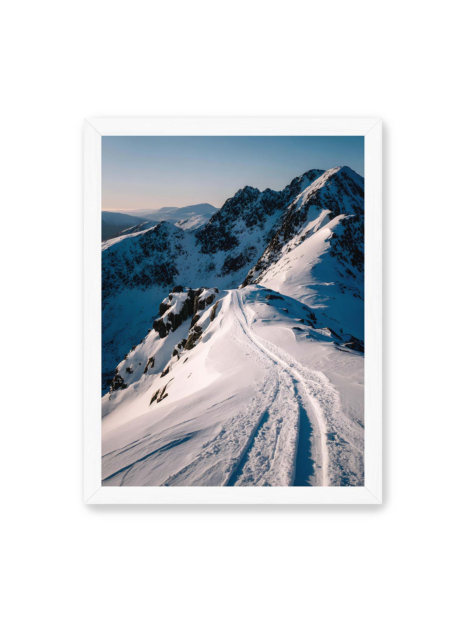 30x40 cm, weißer Rahmen – Verschneiter Bergpfad, sanftes Licht beleuchtet die Spuren im Schnee, Berge im Hintergrund.