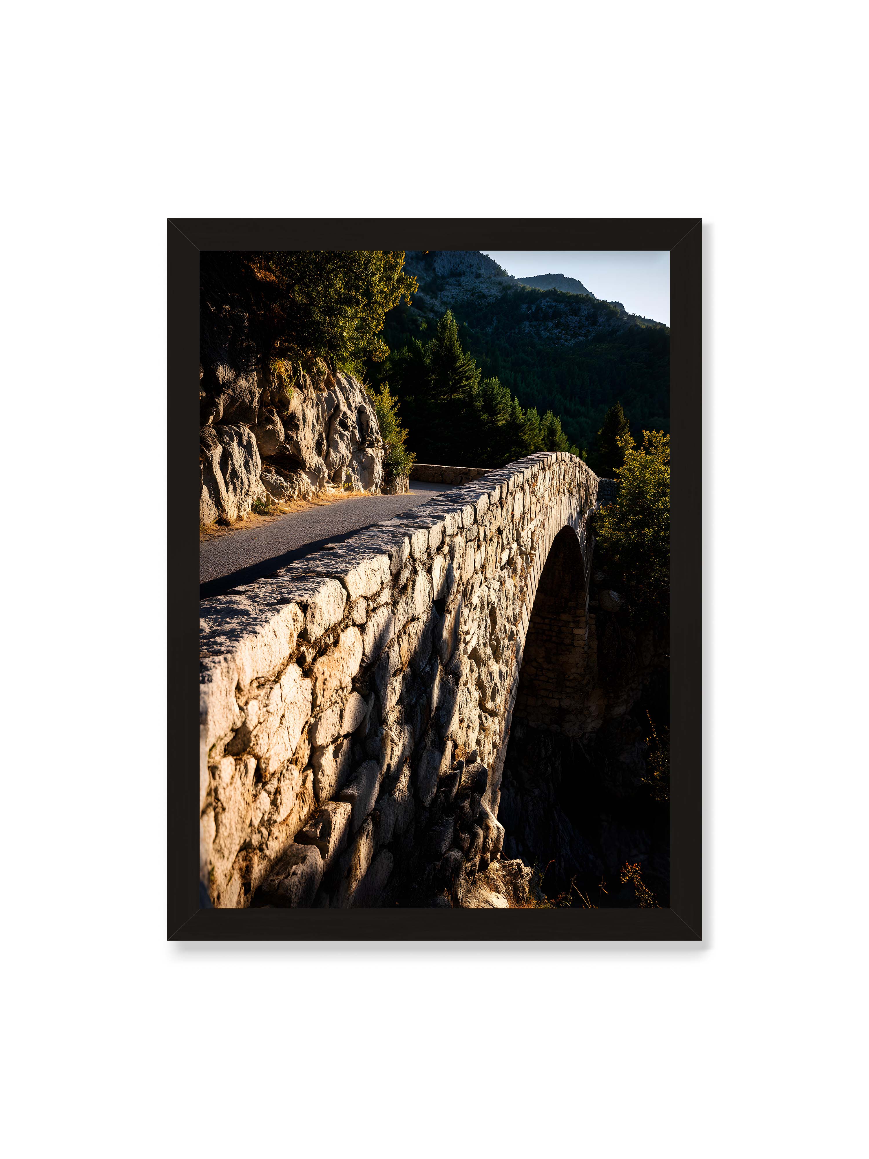 50x70 cm ohne Galerie-Rand mit schwarzem Rahmen – Steinbrücke mit architektonischem Bogen, beleuchtet vom Abendlicht, umrahmt von einer grünen Landschaft.
