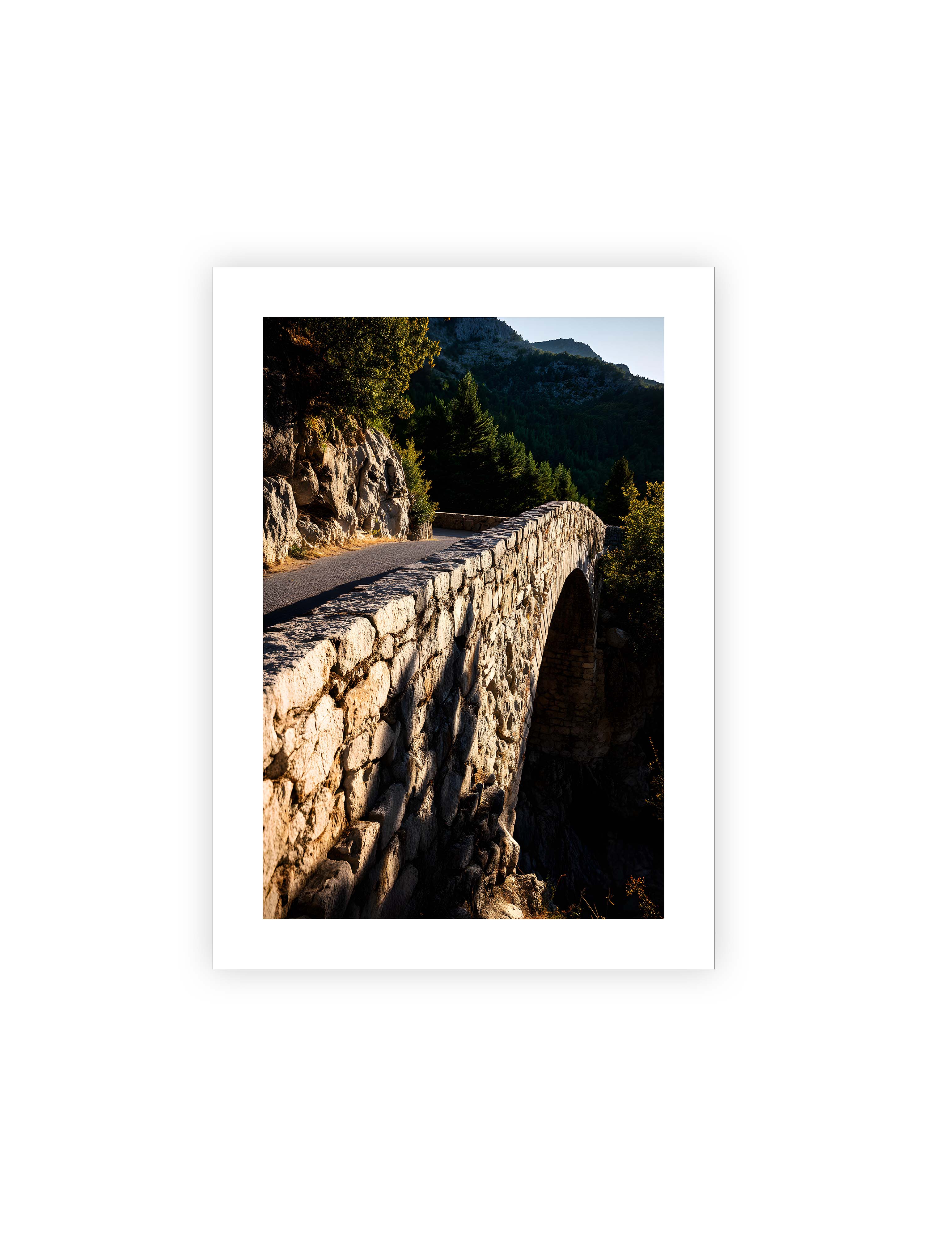 50x70 cm mit weißem Galerie-Rand ohne Rahmen – Steinbrücke mit architektonischem Bogen, beleuchtet vom Abendlicht, umrahmt von einer grünen Landschaft.