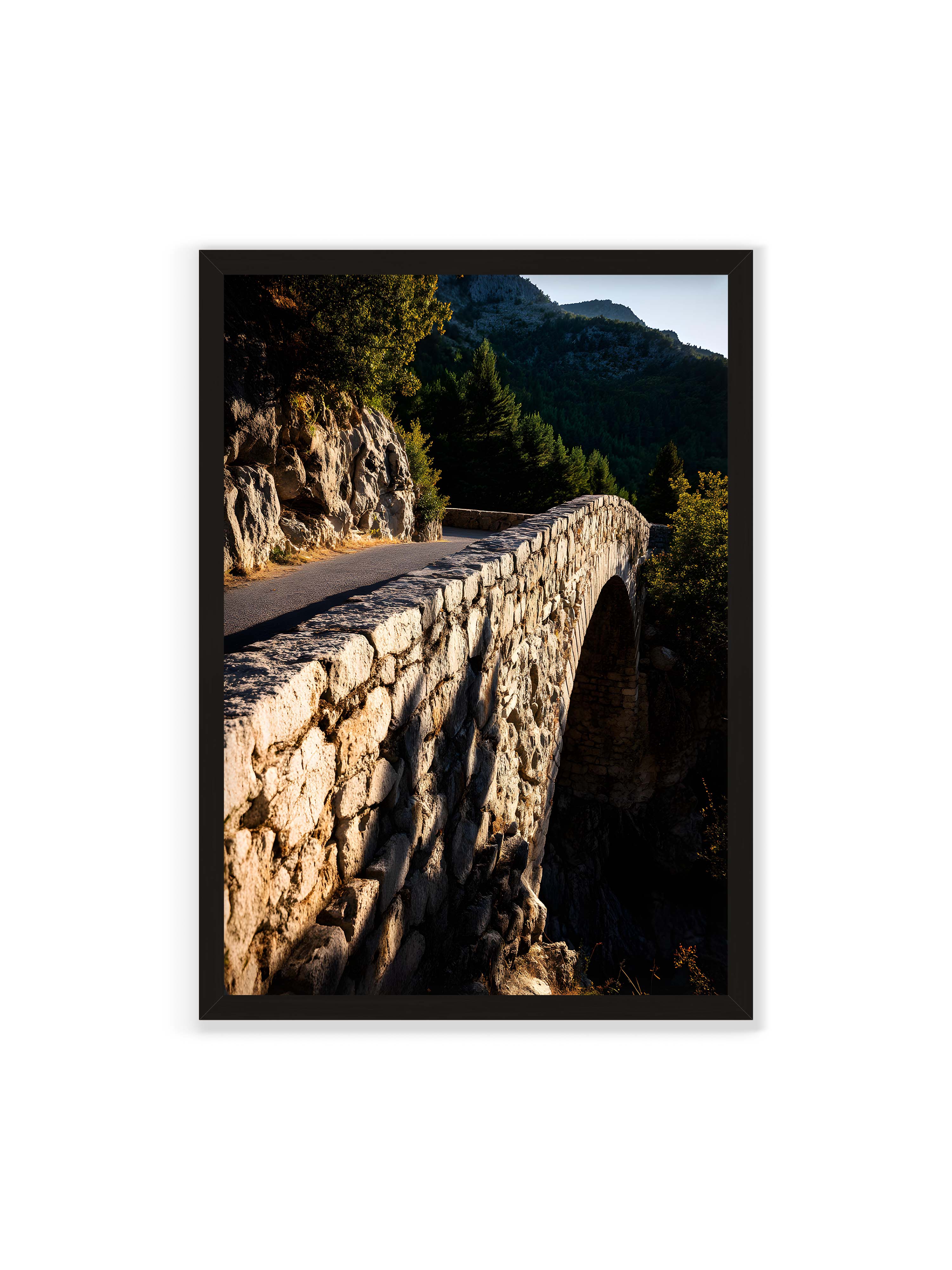 70x100 cm ohne Galerie-Rand mit schwarzem Rahmen – Steinbrücke mit architektonischem Bogen, beleuchtet vom Abendlicht, umrahmt von einer grünen Landschaft.