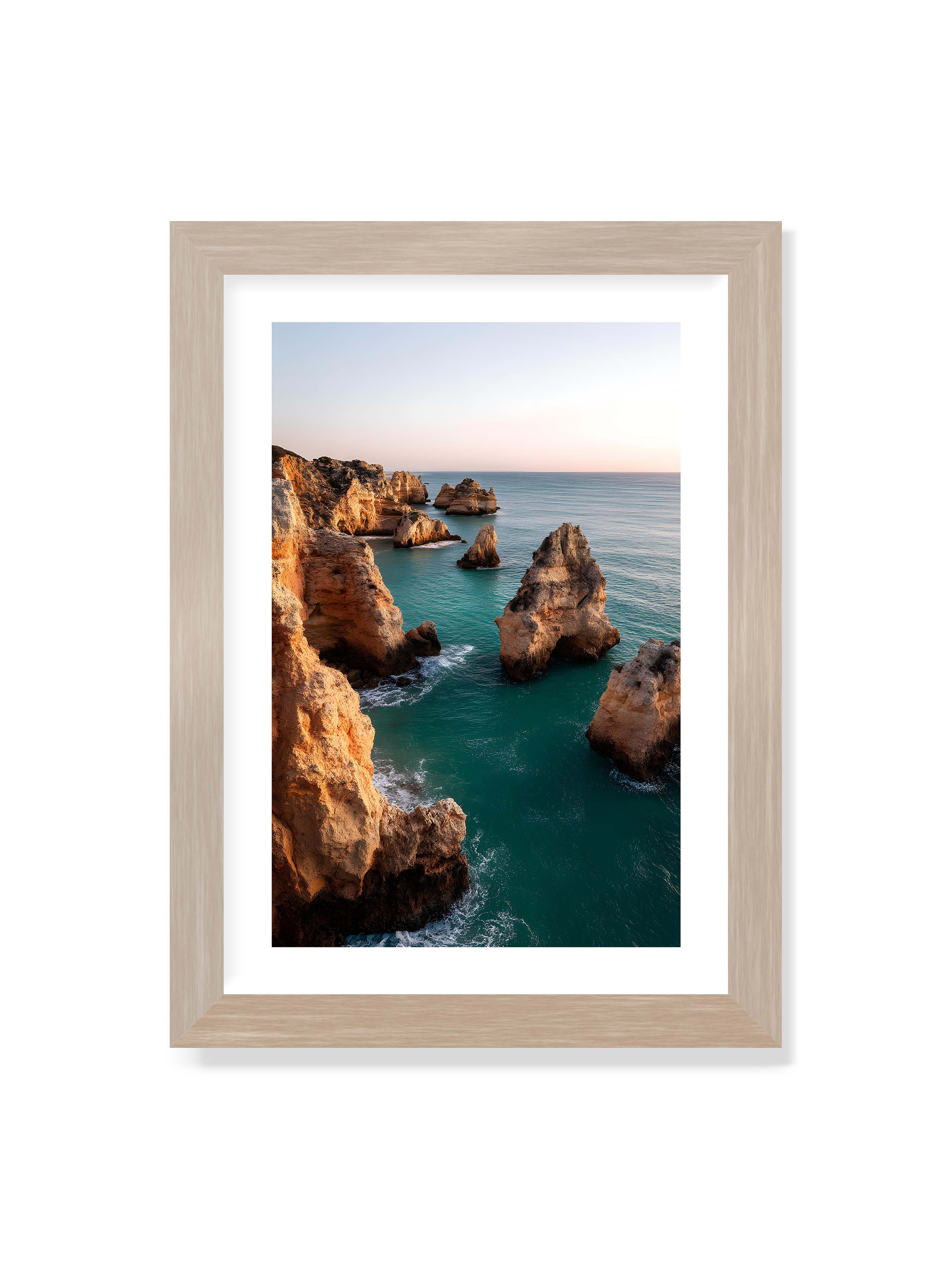 21x30 cm mit weißem Galerie-Rand im Eichenrahmen – Felsformationen an der Küste, umgeben von azurblauem Wasser und goldenem Licht des späten Nachmittags.