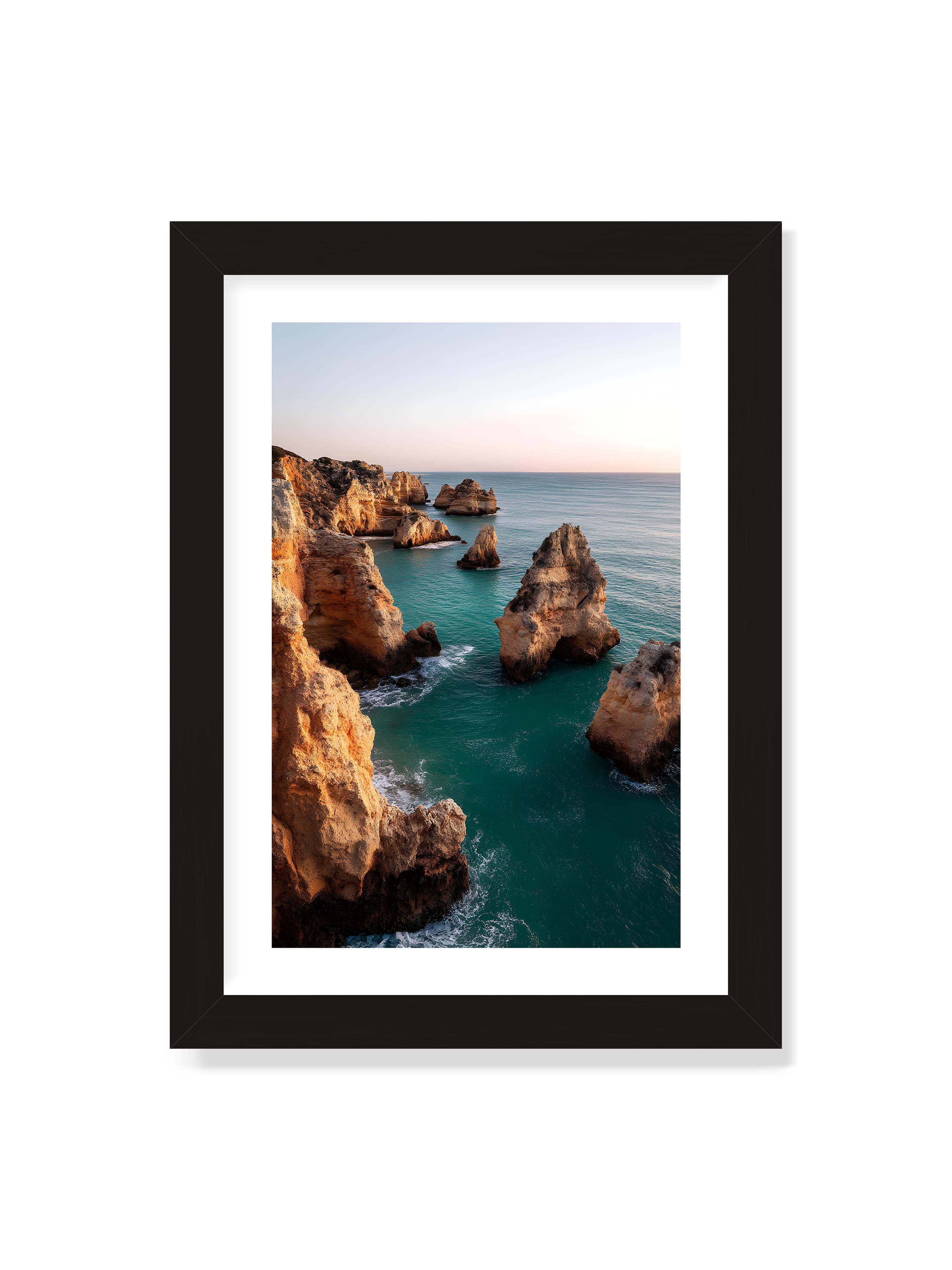 21x30 cm mit weißem Galerie-Rand mit schwarzem Rahmen – Felsformationen an der Küste, umgeben von azurblauem Wasser und goldenem Licht des späten Nachmittags.