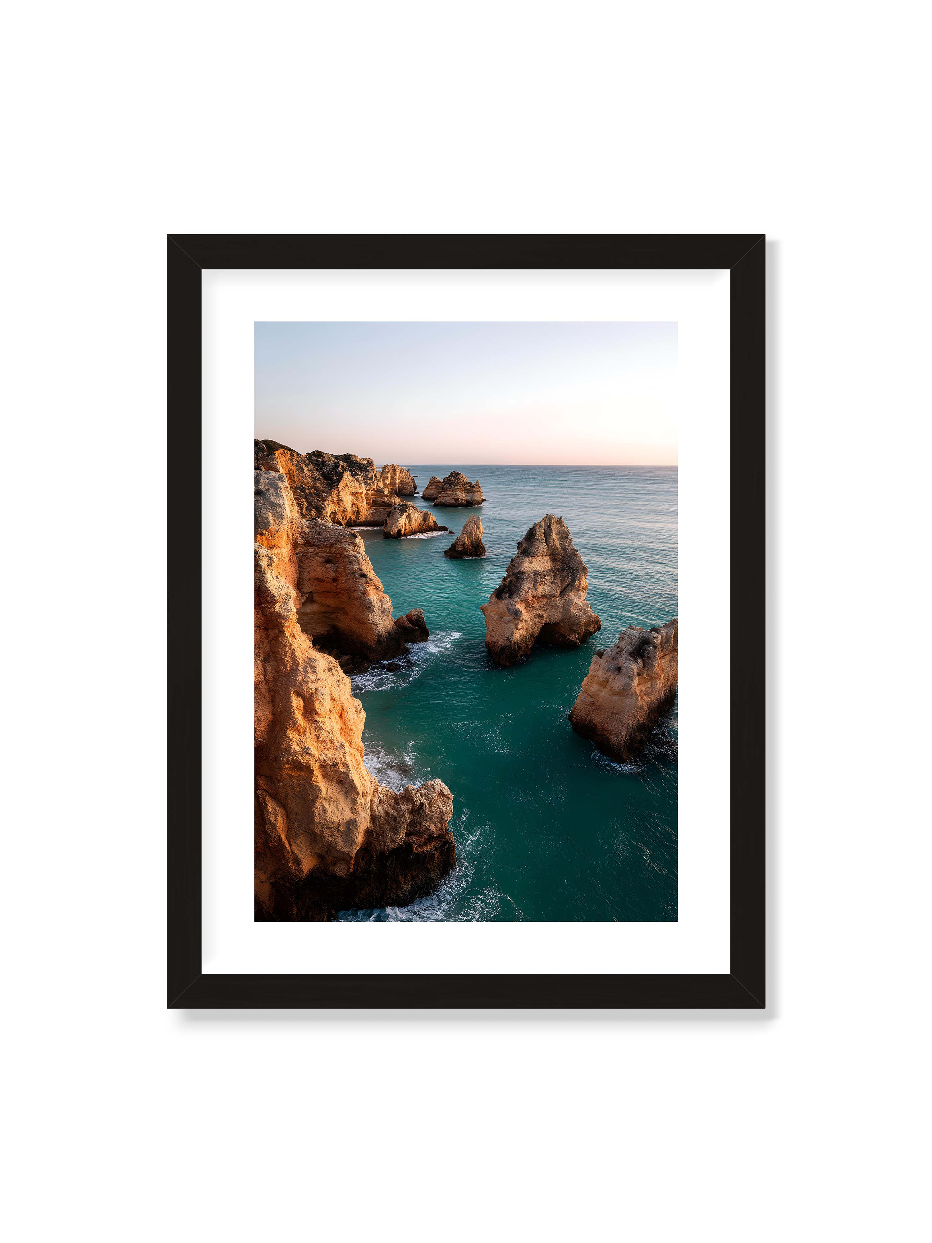 30x40 cm mit weißem Galerie-Rand mit schwarzem Rahmen – Felsformationen an der Küste, umgeben von azurblauem Wasser und goldenem Licht des späten Nachmittags.