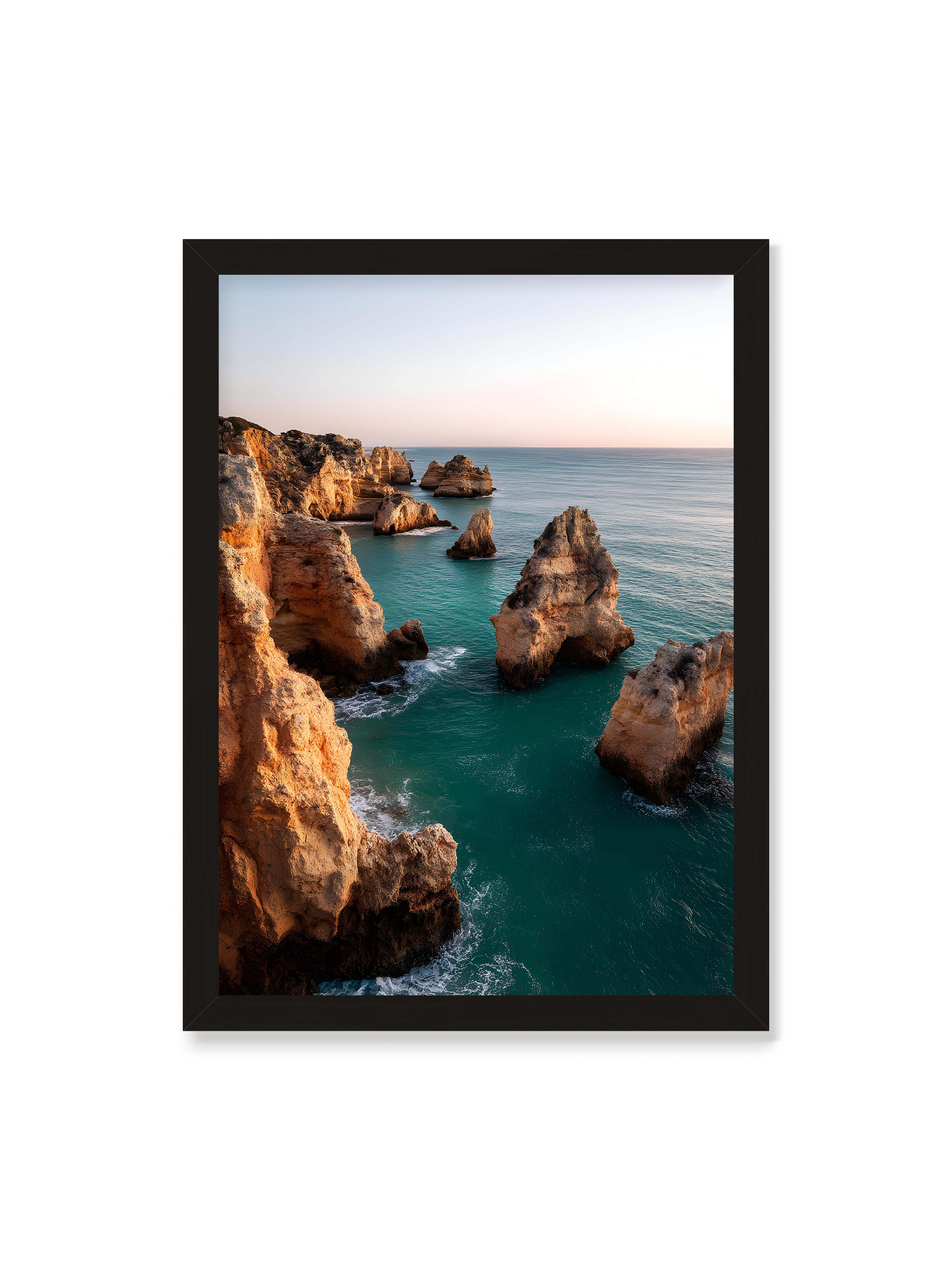 50x70 cm ohne Galerie-Rand mit schwarzem Rahmen – Felsformationen an der Küste, umgeben von azurblauem Wasser und goldenem Licht des späten Nachmittags.