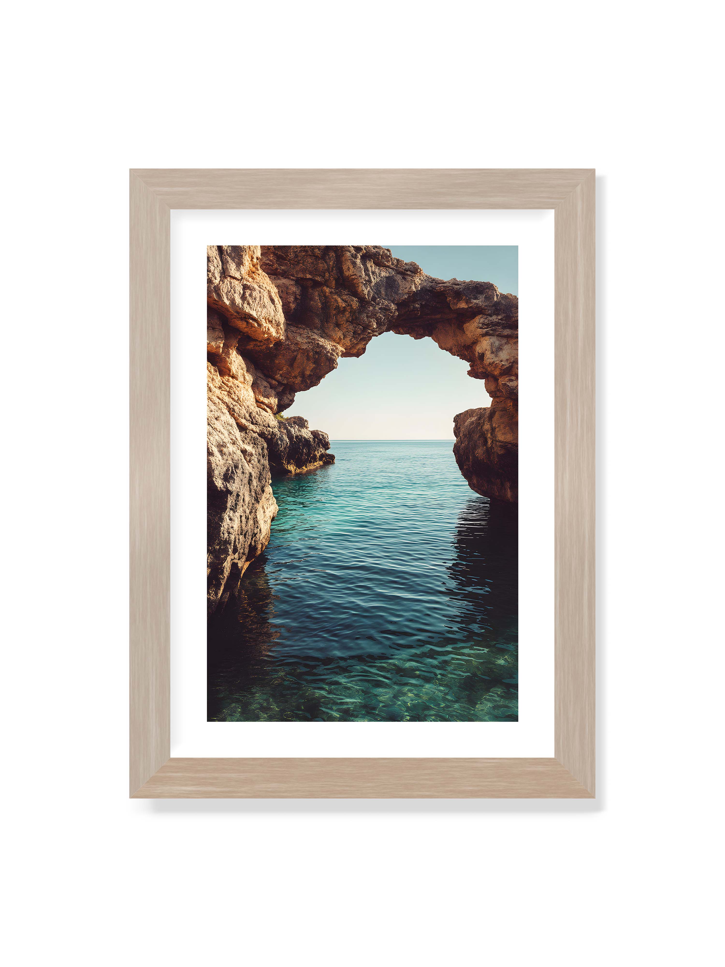 21x30 cm mit weißem Galerie-Rand im Eichenrahmen – Felsenbogen mit Blick auf das klare, türkisfarbene Meer und die weite Küstenlandschaft.