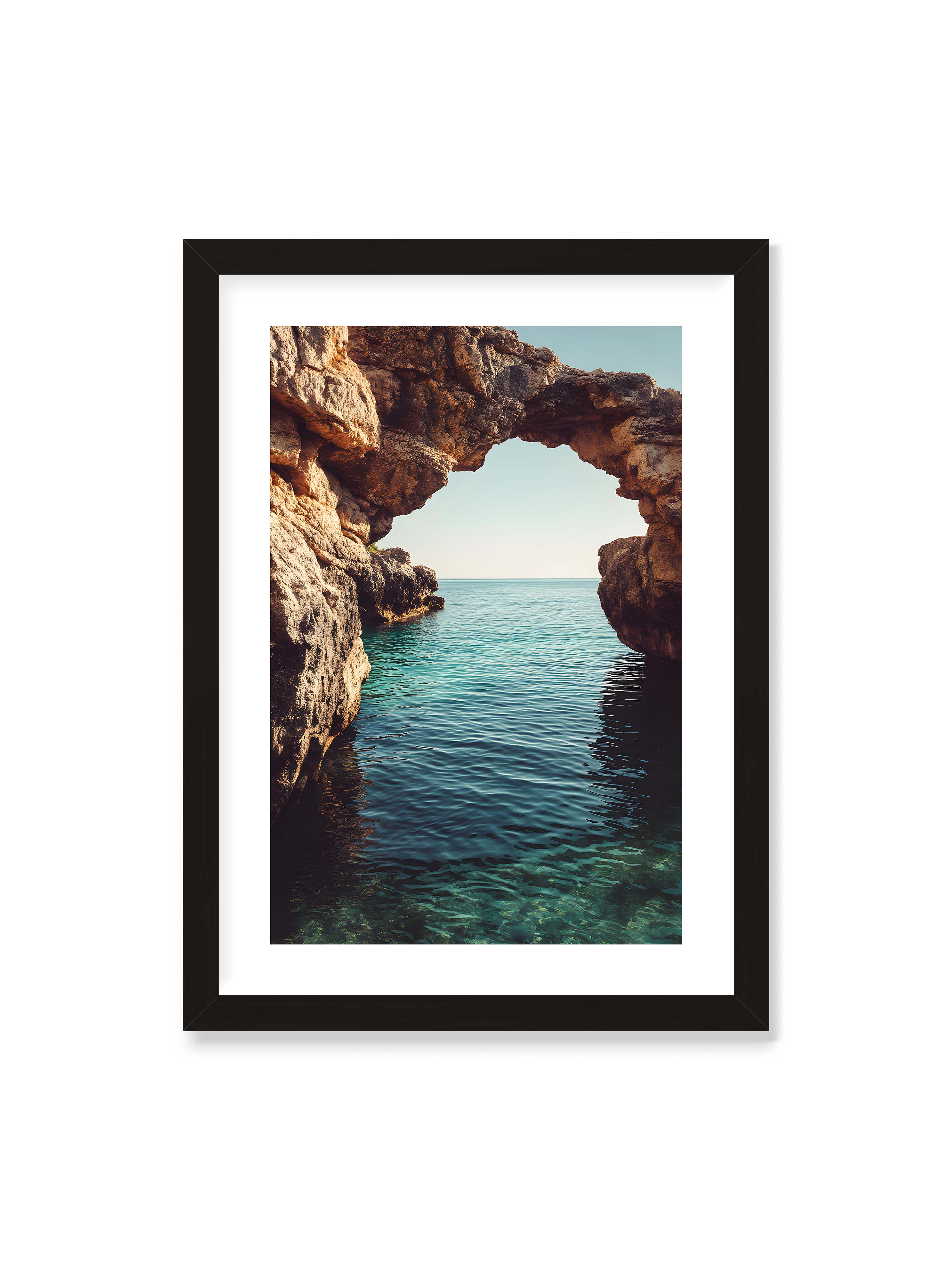 50x70 cm mit weißem Galerie-Rand mit schwarzem Rahmen – Felsenbogen mit Blick auf das klare, türkisfarbene Meer und die weite Küstenlandschaft.