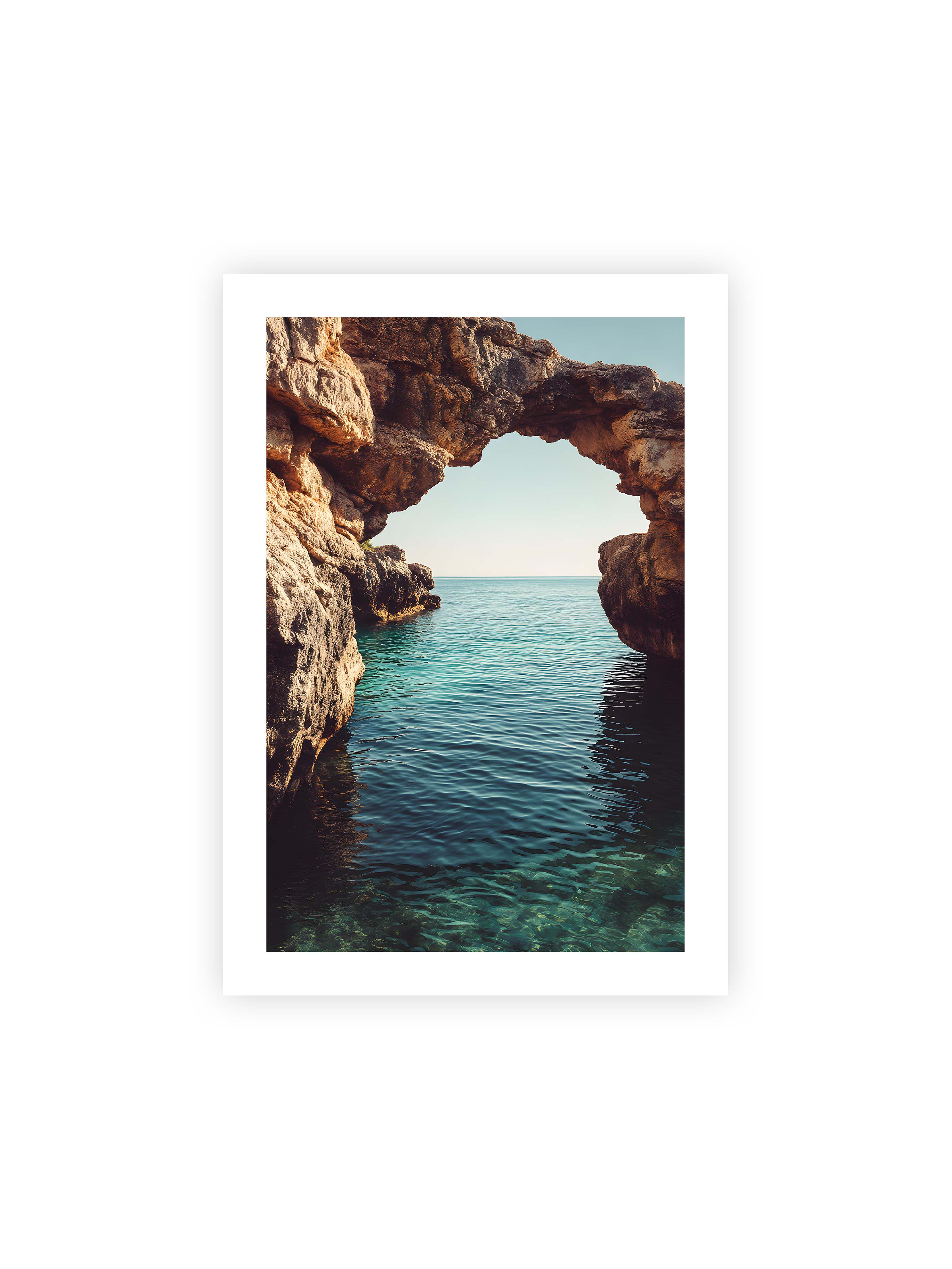 70x100 cm mit weißem Galerie-Rand ohne Rahmen – Felsenbogen mit Blick auf das klare, türkisfarbene Meer und die weite Küstenlandschaft.