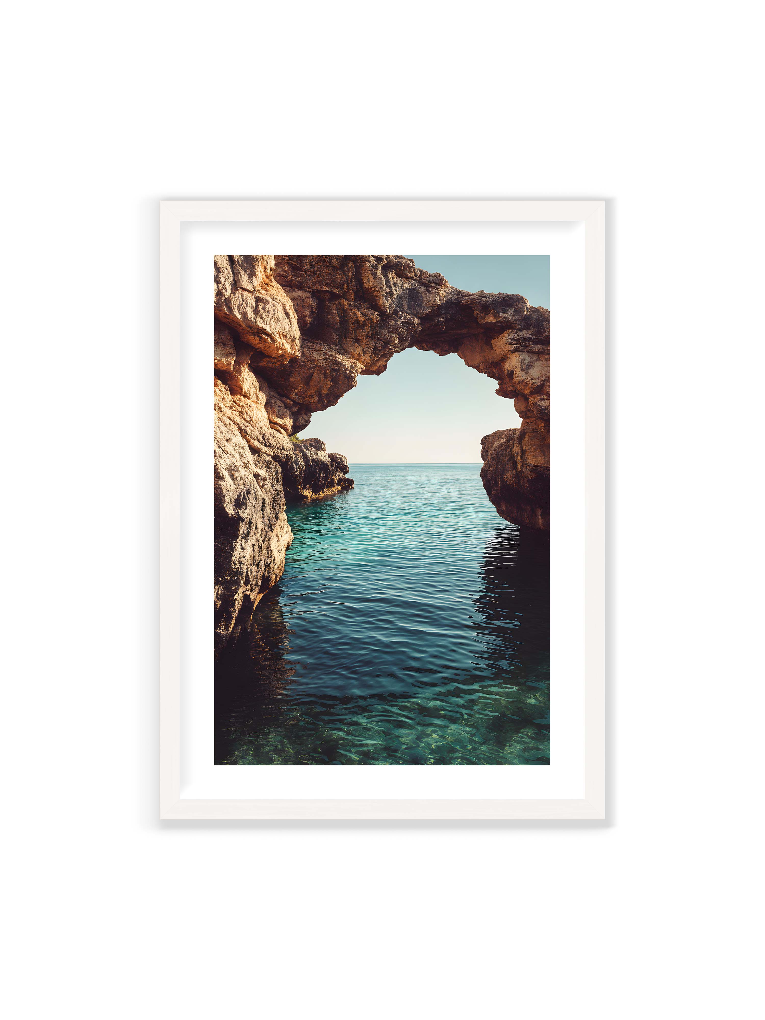 70x100 cm mit weißem Galerie-Rand mit weißem Rahmen – Felsenbogen mit Blick auf das klare, türkisfarbene Meer und die weite Küstenlandschaft.