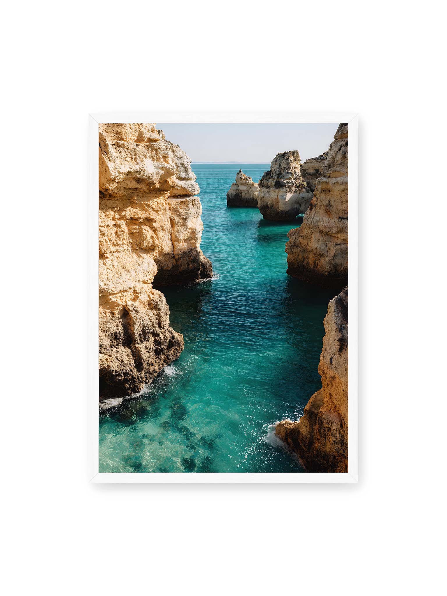 50x70 cm, weißer Rahmen – Mehrere Felsen an einer Küste der Algarve, umgeben von klarem, türkisfarbenem Wasser, das sanft an die Klippen schwappt.