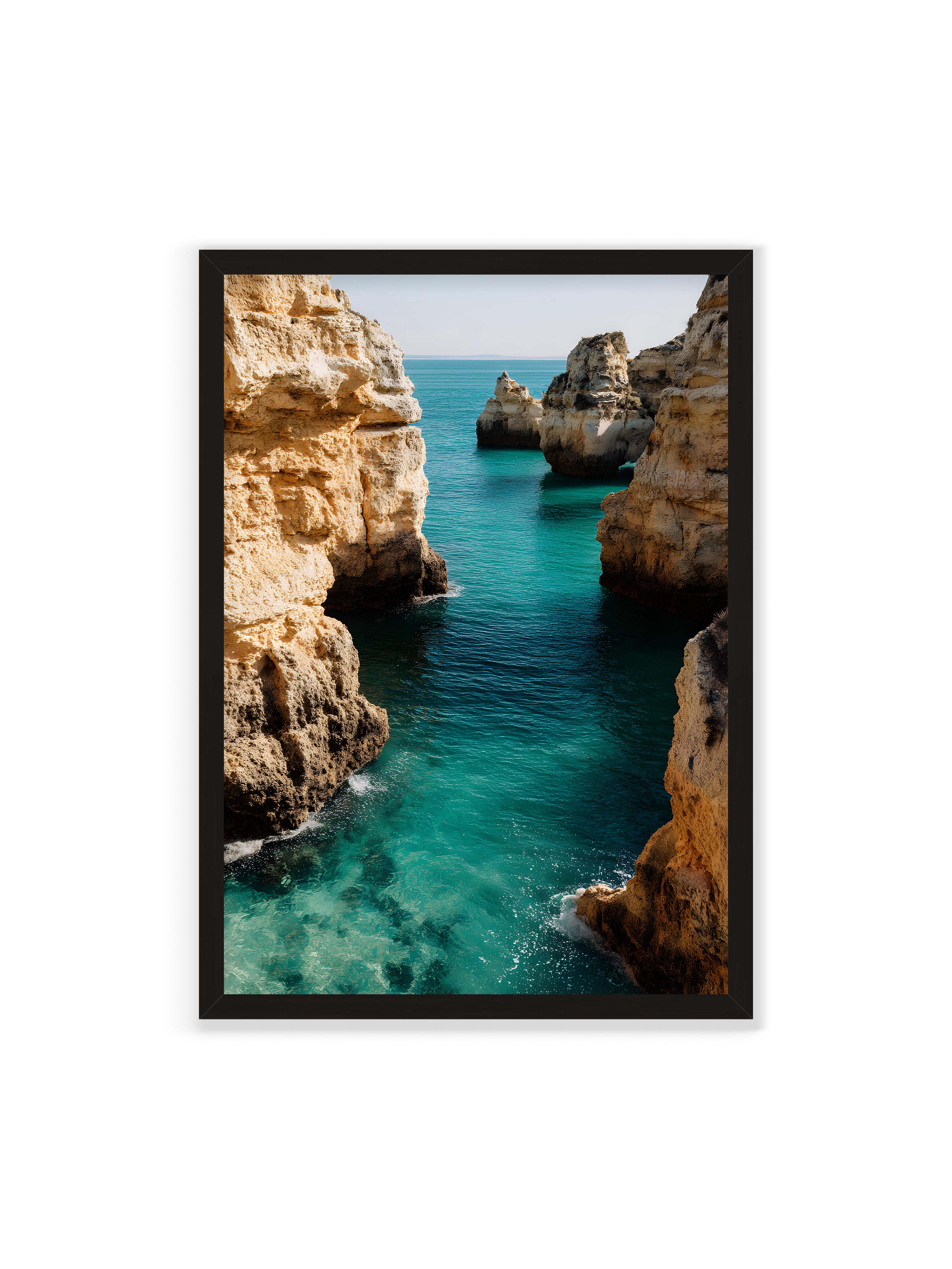 70x100 cm ohne Galerie-Rand mit schwarzem Rahmen – Felsen an einer Küste, umgeben von klarem, türkisfarbenem Wasser, das sanft an die Klippen schwappt.