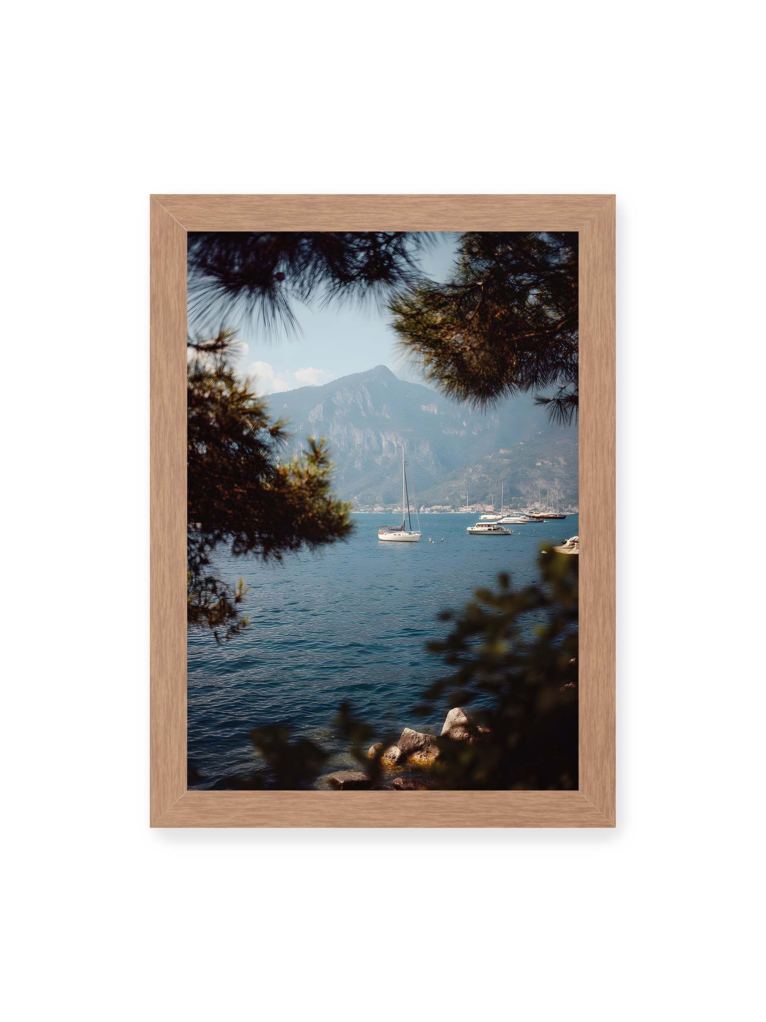 21x30 cm, Eichenrahmen – Segelboote im ruhigen Wasser vor Bergen, eingerahmt von unscharfen Ästen im Vordergrund.