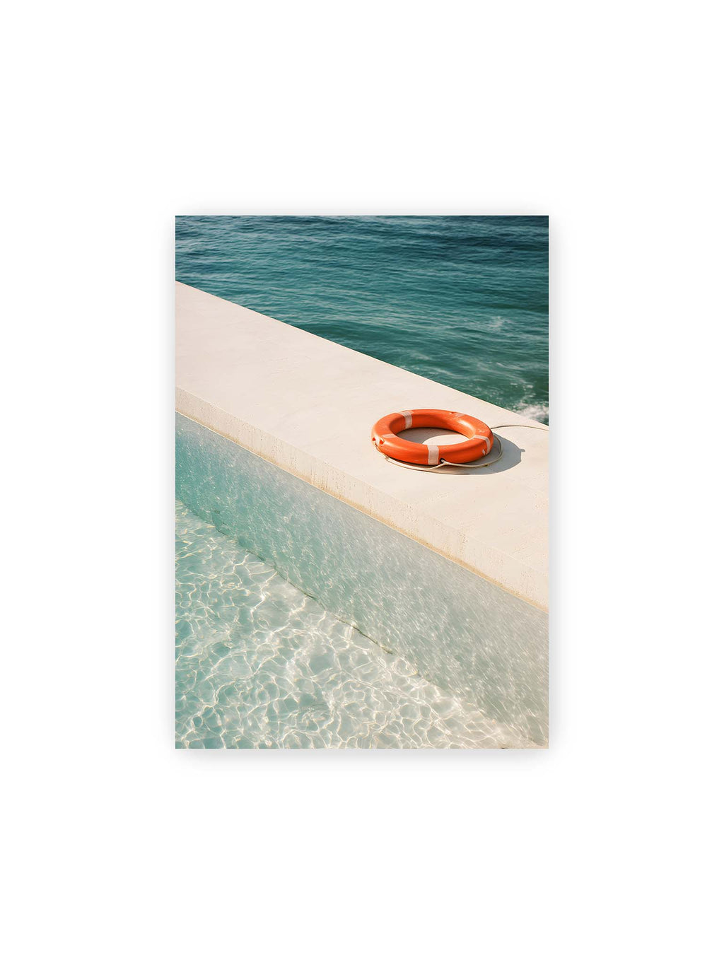 21x30 cm – Rettungsring liegt auf heller Kante zwischen Poolwasser und offenem Meer mit klarer Trennung der Flächen.