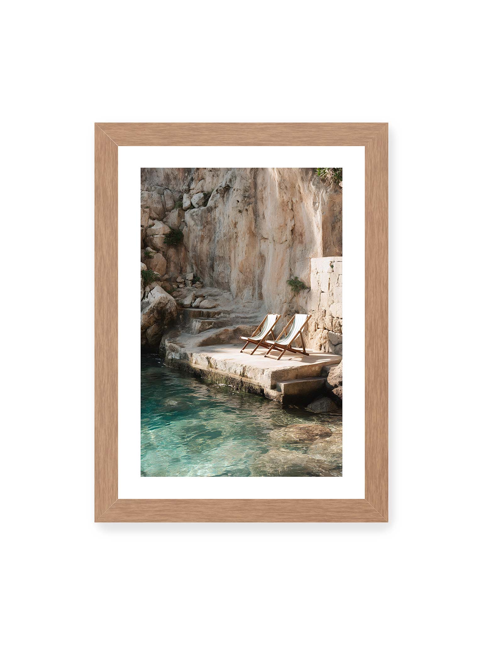 21x30 cm, weißer Galerie-Rand, Eichenrahmen – Zwei Liegestühle auf Felsplattform am klaren Wasser, umgeben von rauer Küstenwand und sanftem Licht.